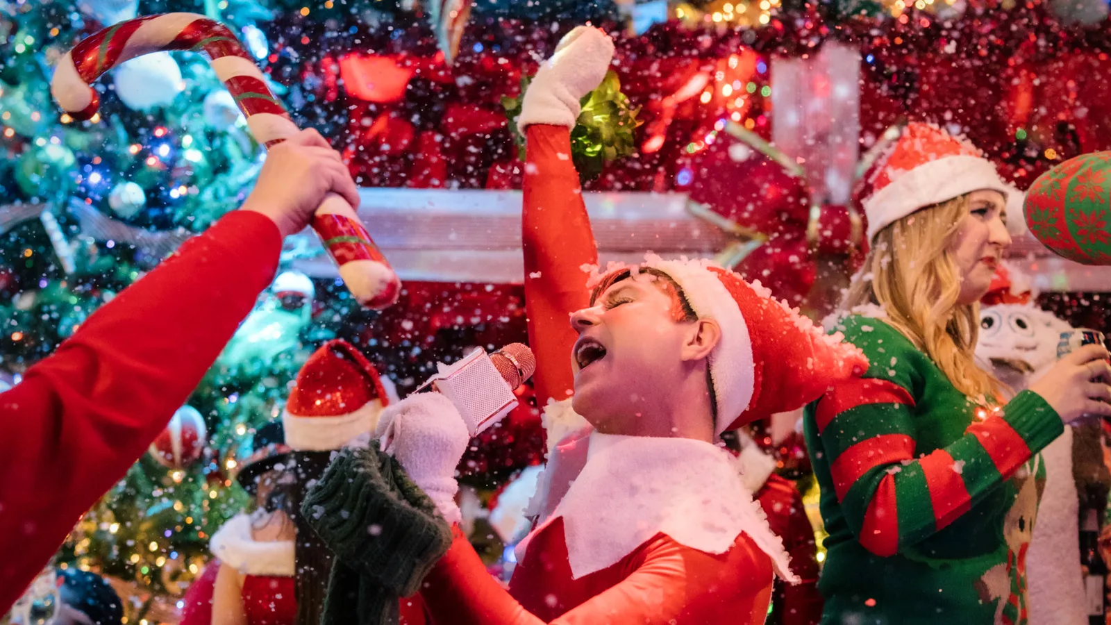Guests sing and dance with giant candy canes inside Frosty's Christmas Bar pop-up in Hollywood