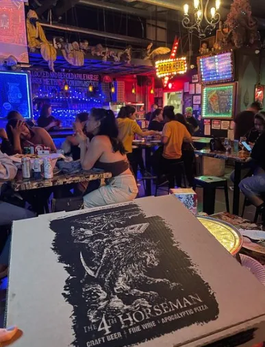 A dark bar with a large pizza box on the table at The 4th Horseman