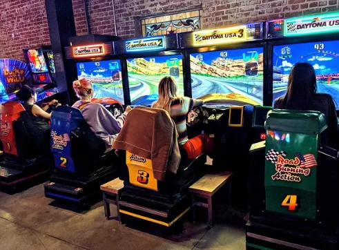 Players at a racing game inside Barcade, Highland Park