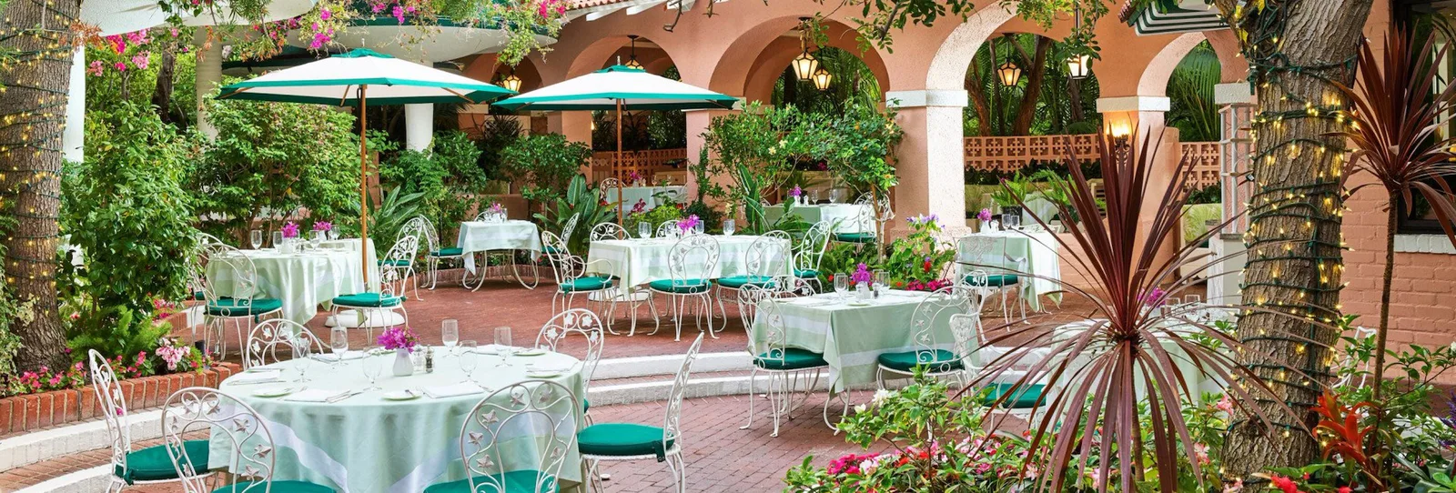 Garden patio with green umbrellas and white wrought iron furniture