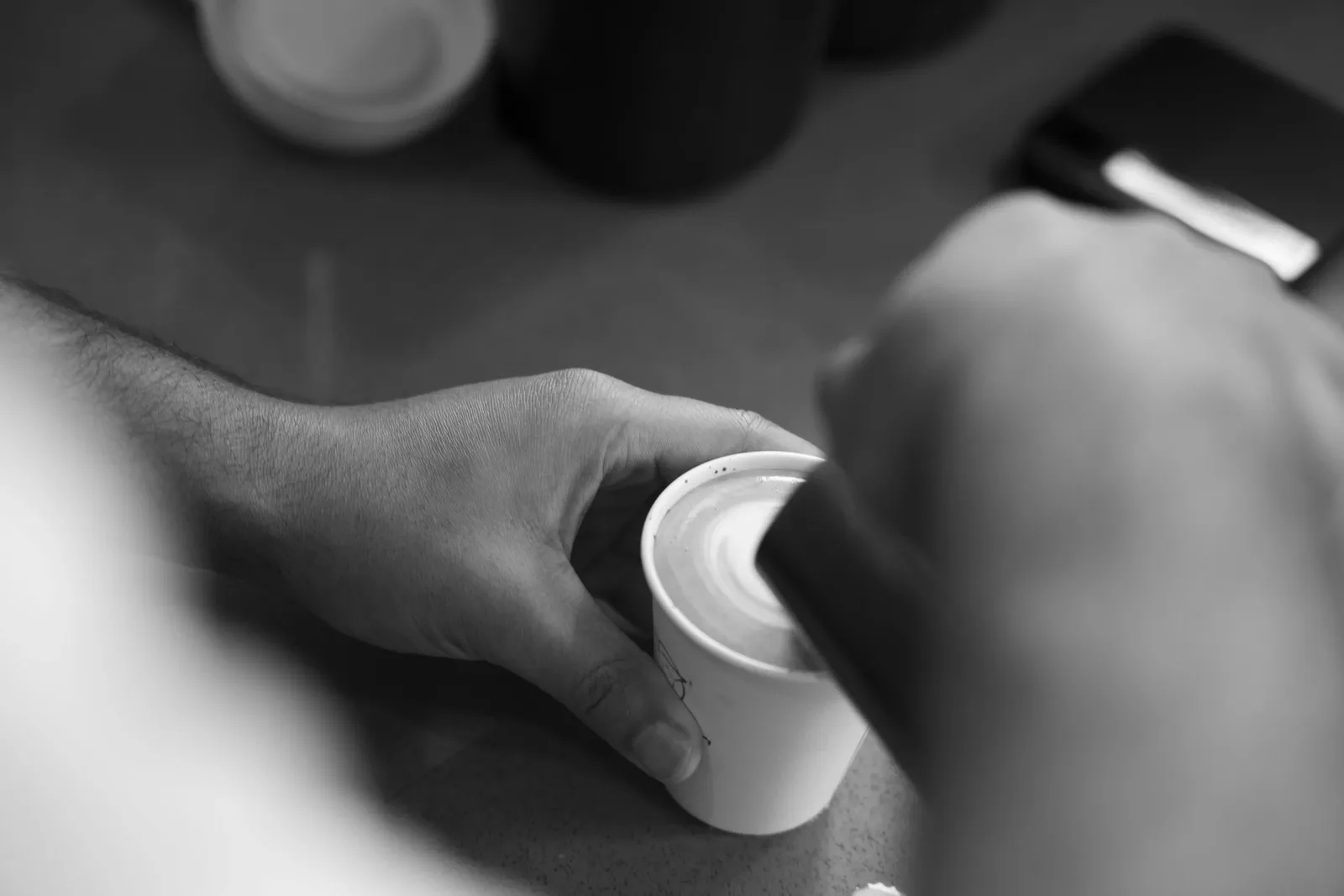 Black and white close up of a hand setting down a cup