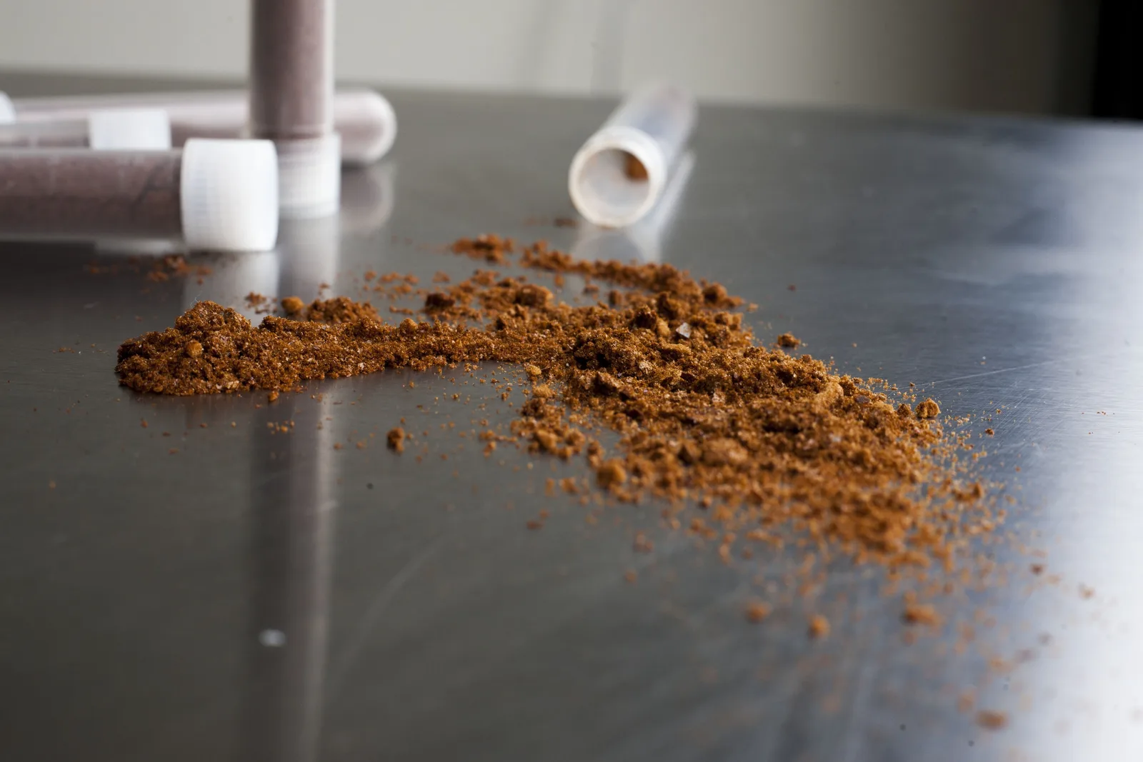 Close-up of ground coffee and portafilter parts on steel