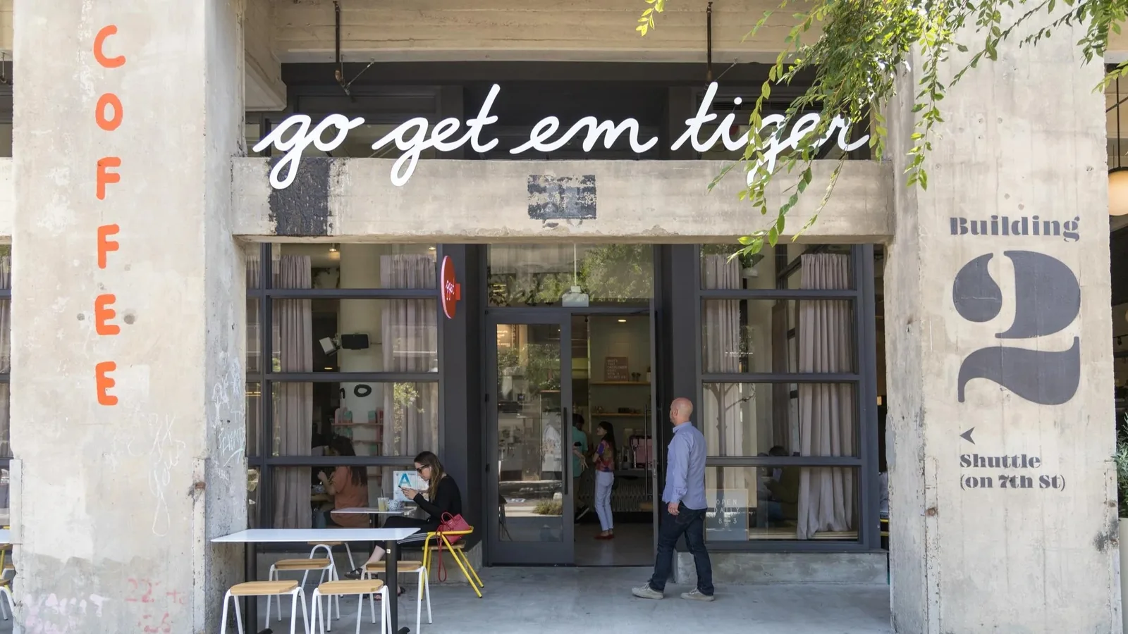 Cafe storefront with script signage and sidewalk seating on a corner