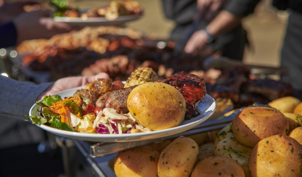 A plate of wood-fired barbecue, tri-tip, sausage, salad and a garlic roll, at Wood Ranch BBQ & Grill in Los Angeles.