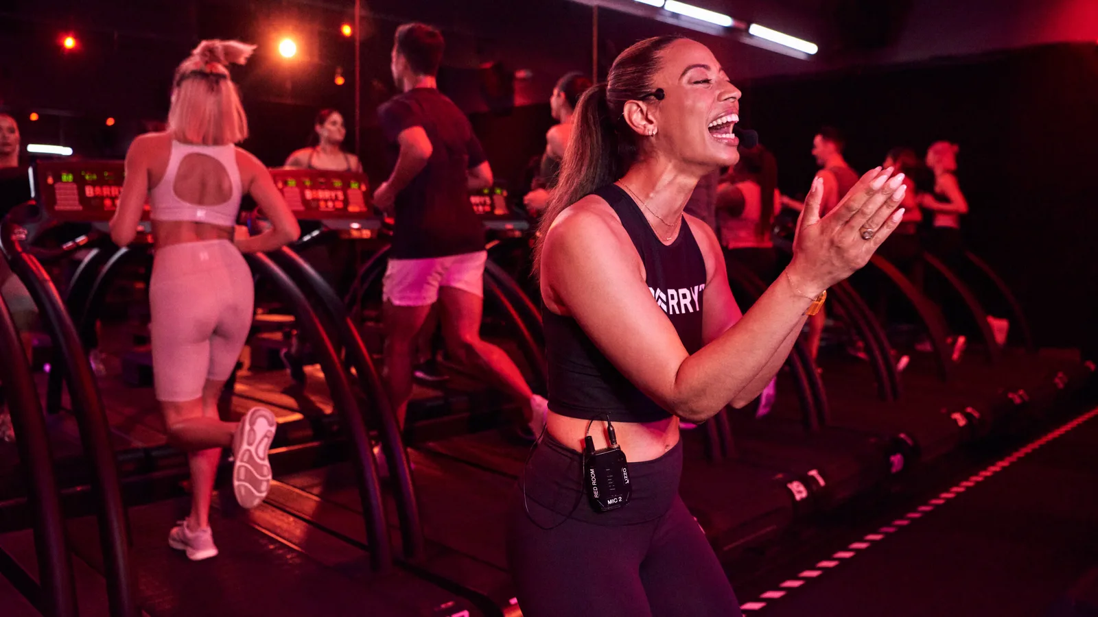 High-energy red-lit Barry's class with members on treadmills and weights