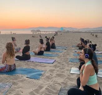 Outdoor beach yoga class near the Rainbow Tower on Venice Beach with Westside Yogis