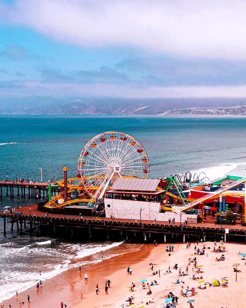 The Santa Monica Pier and Pacific Park from above on a packed beach day