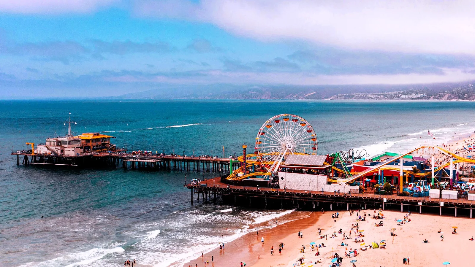Crowds filling the beach around the Santa Monica Pier and Pacific Park