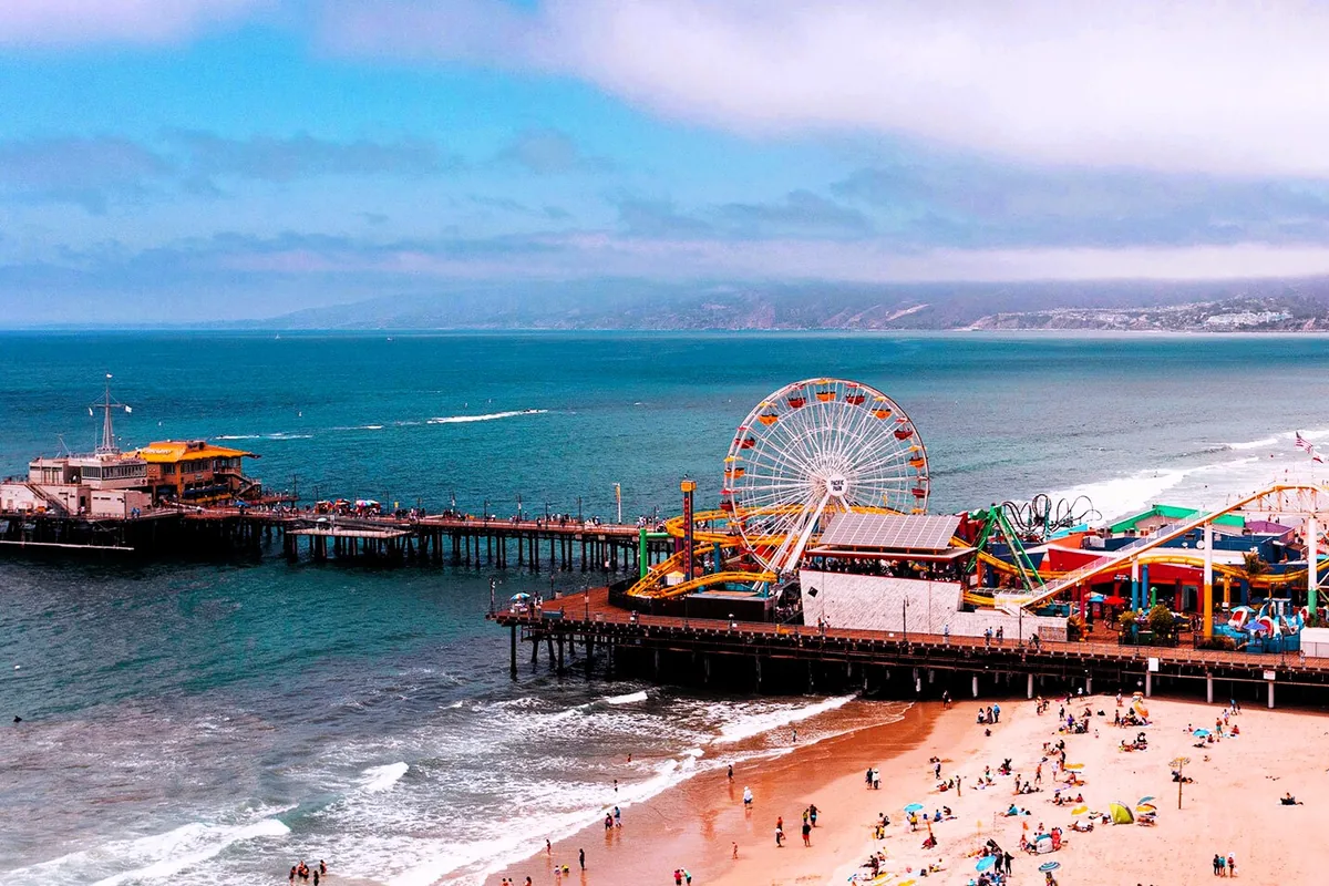The Santa Monica Pier and Pacific Park from above on a packed beach day