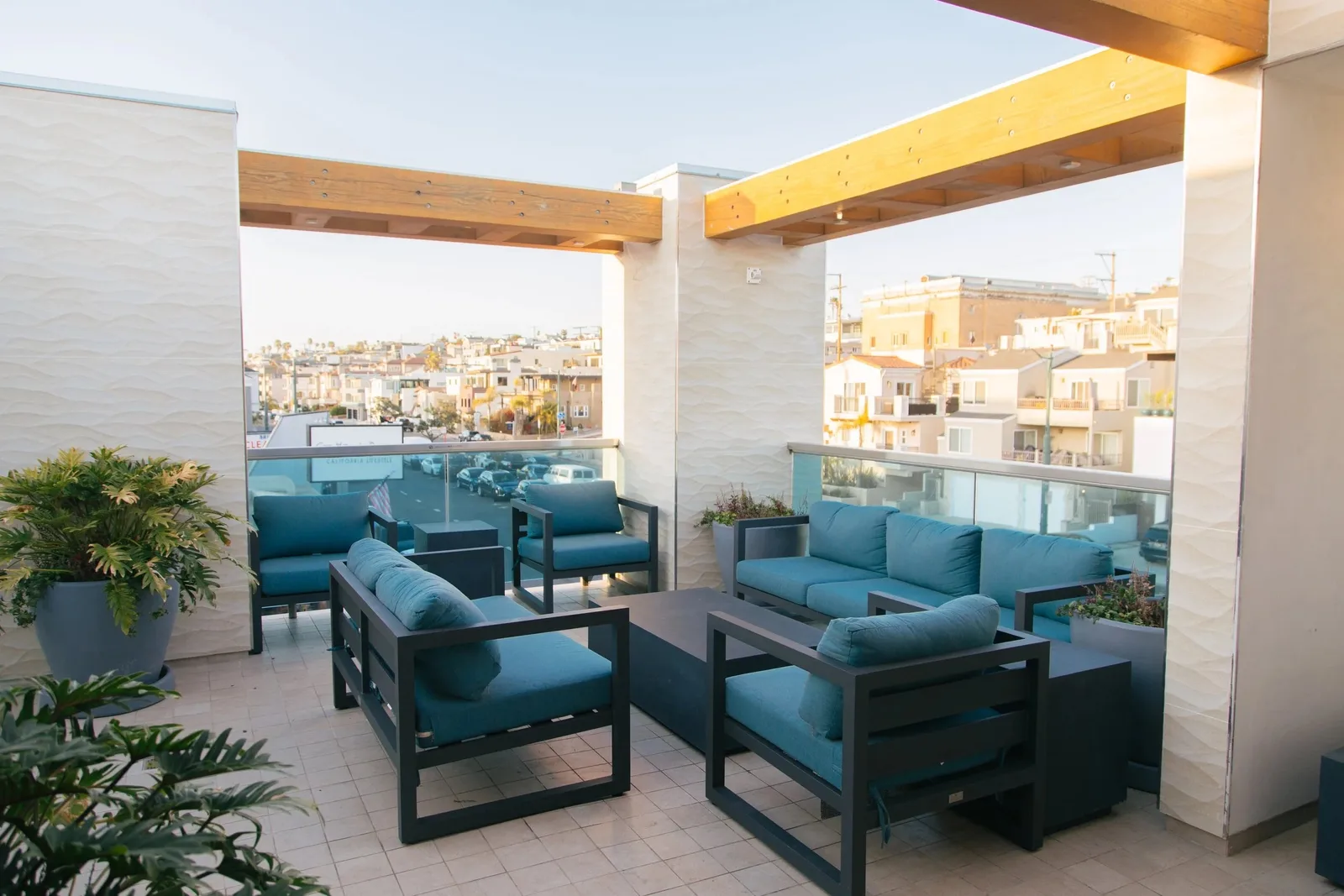 Rooftop lounge with teal armchairs under a wooden pergola