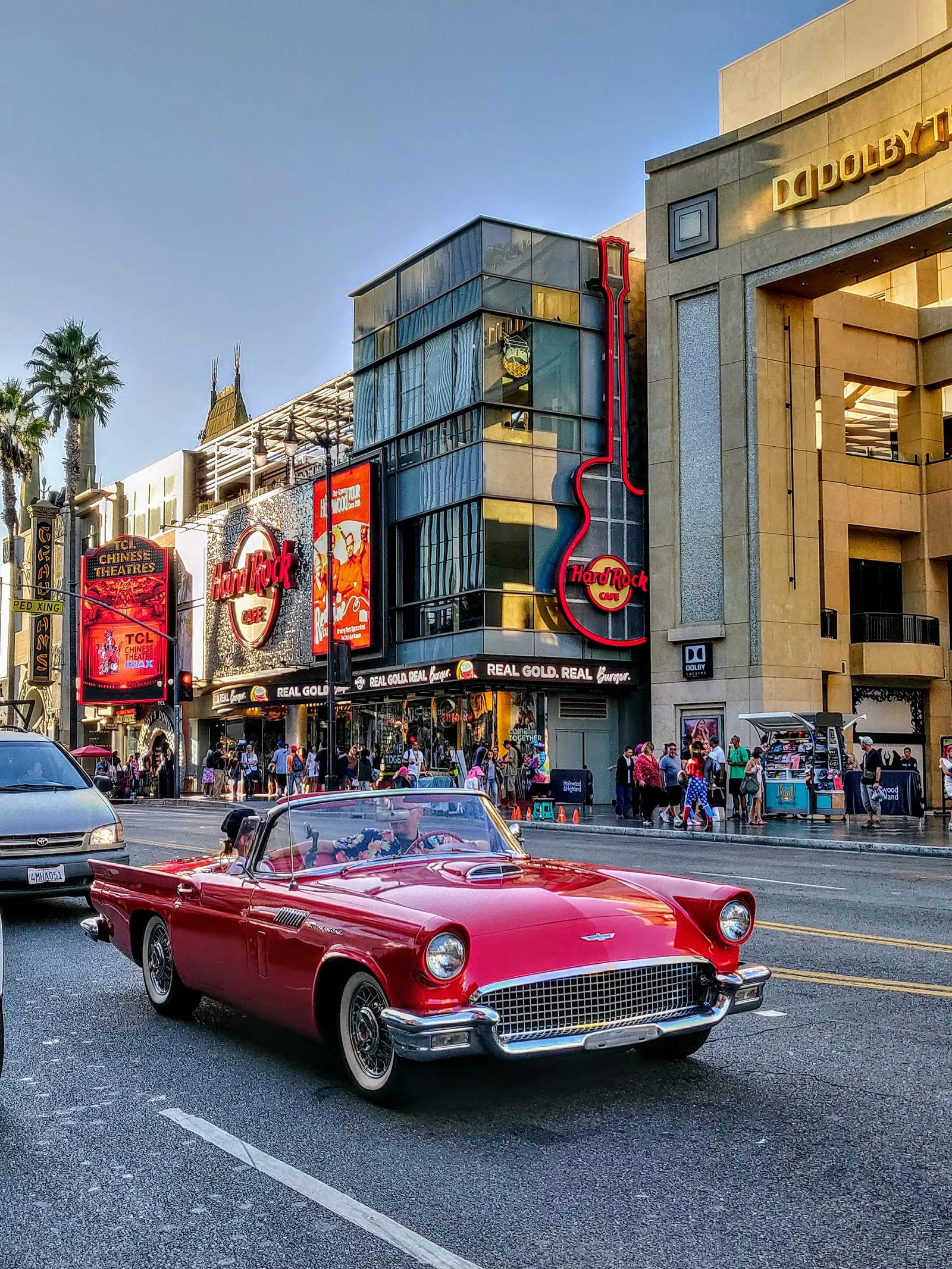 Busy boulevard with a red vintage convertible and crowded sidewalks