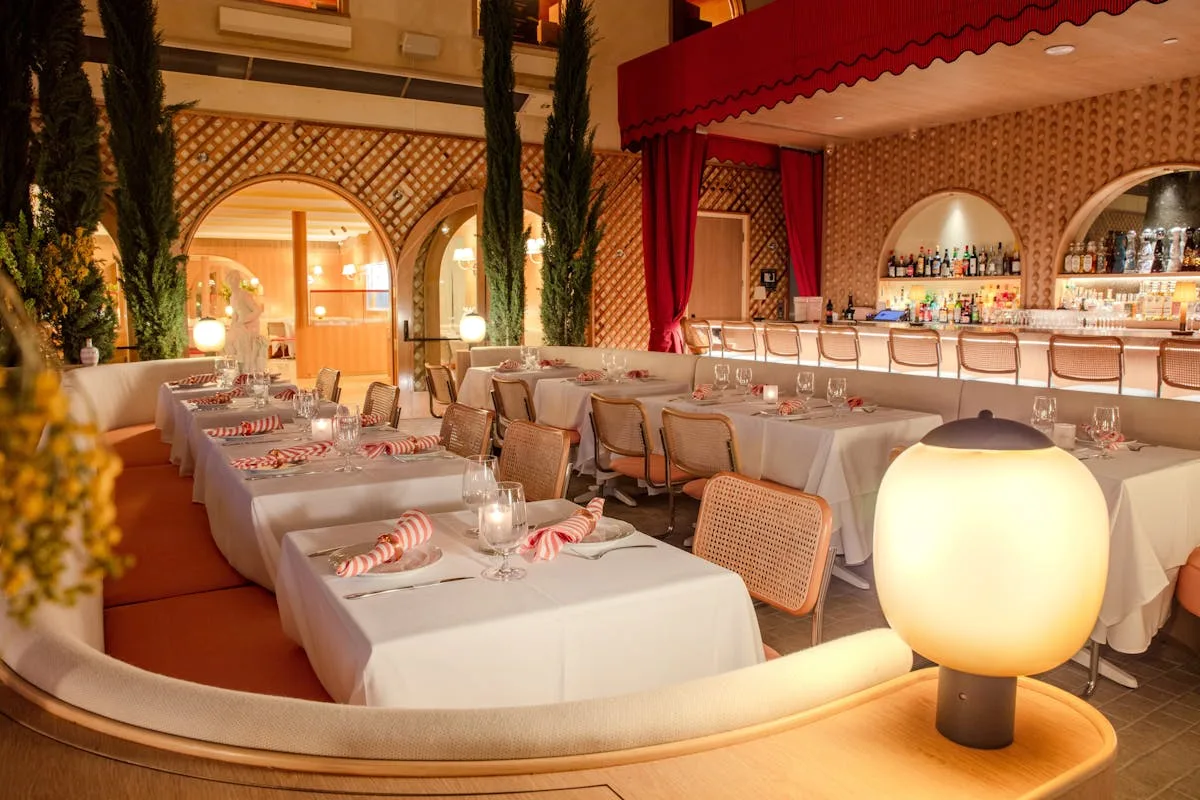 Long dining room with white clothed tables and arched red drapery
