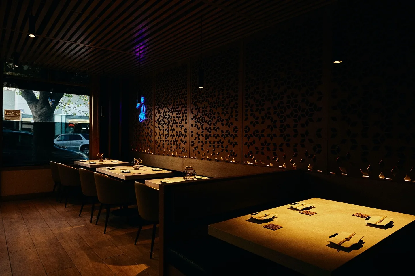 Dim dining room with a slatted wood ceiling and lit tabletops