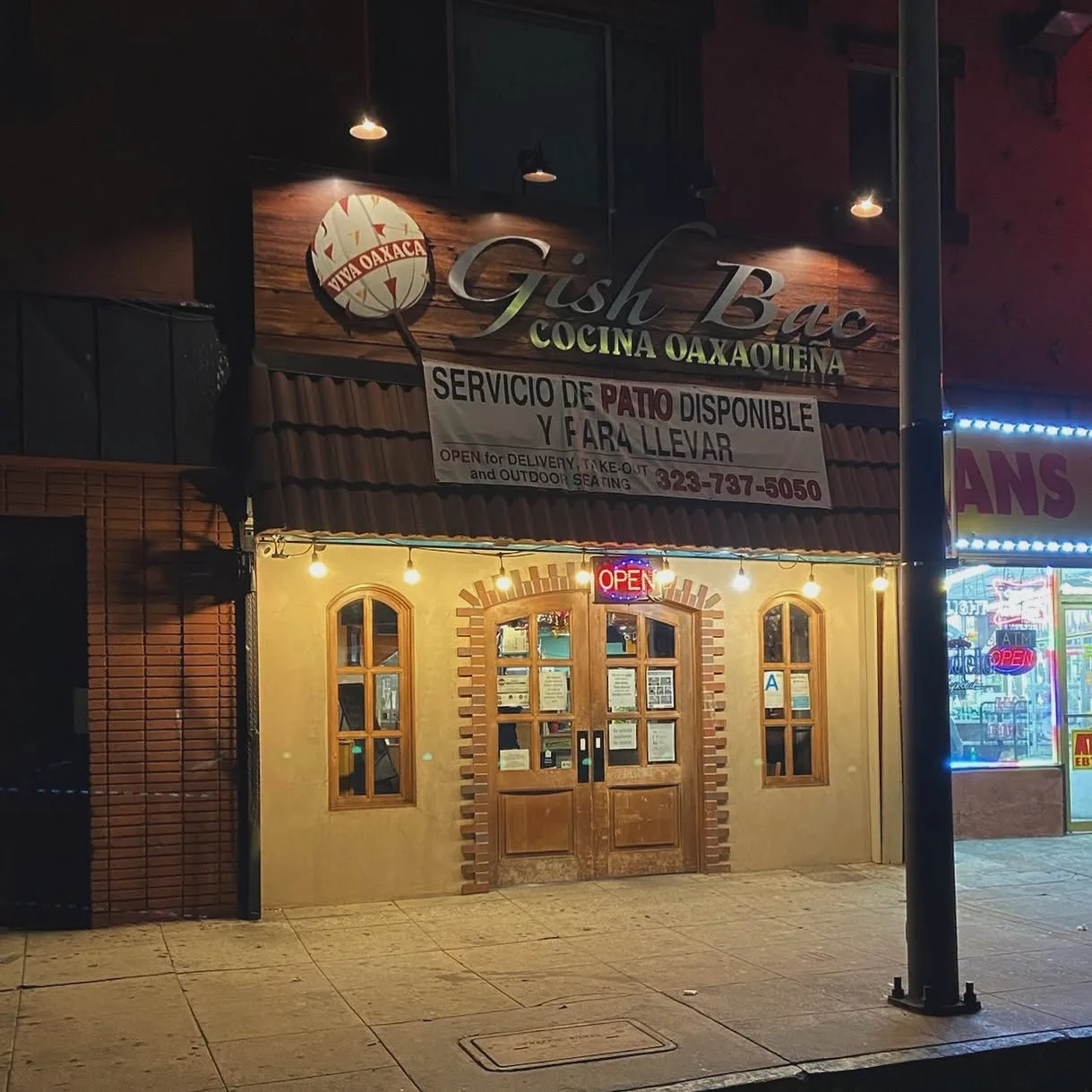 Restaurant storefront at night with awning signage and lit windows