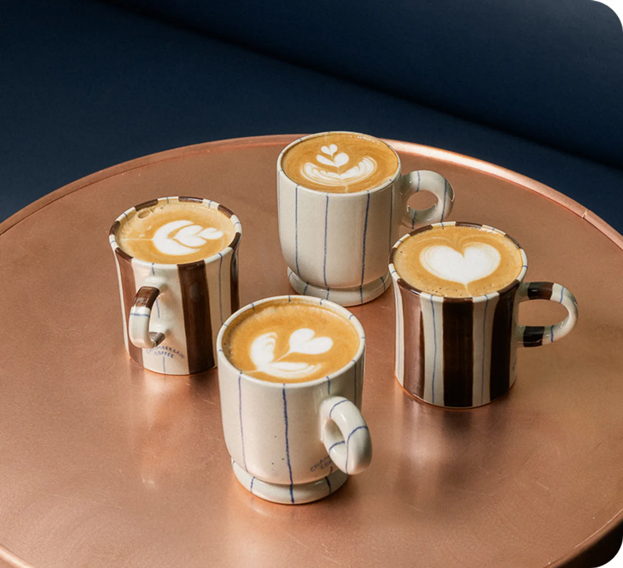 Four cups of latte art arranged on a round table