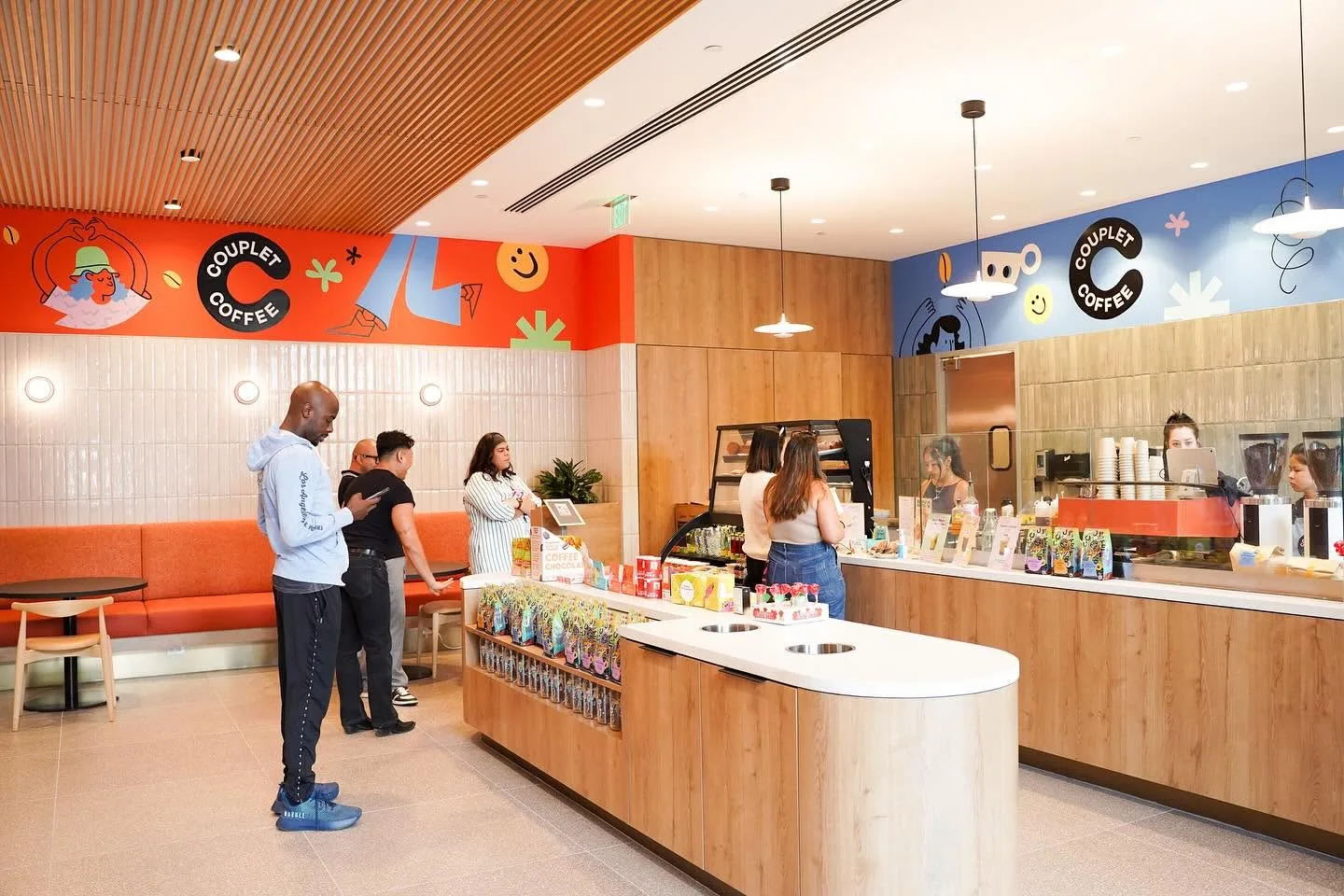 Bright cafe interior with customers standing at a curved counter