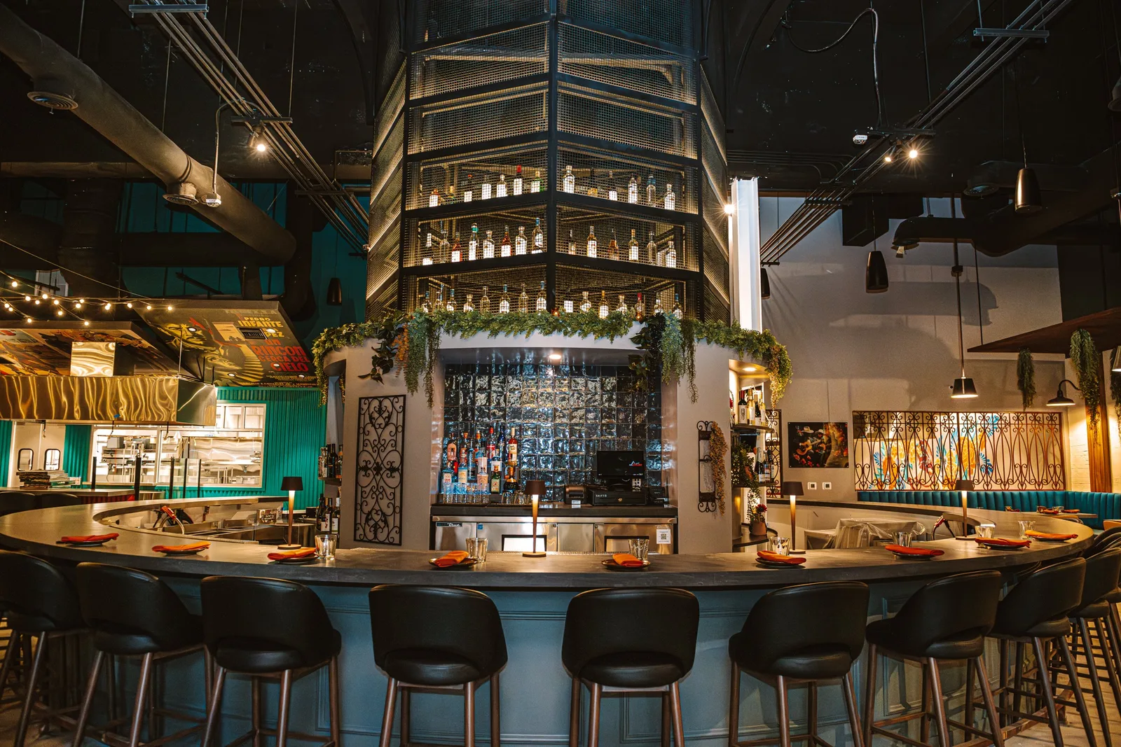 Bar with tall bottle shelving, hanging lights and counter stools