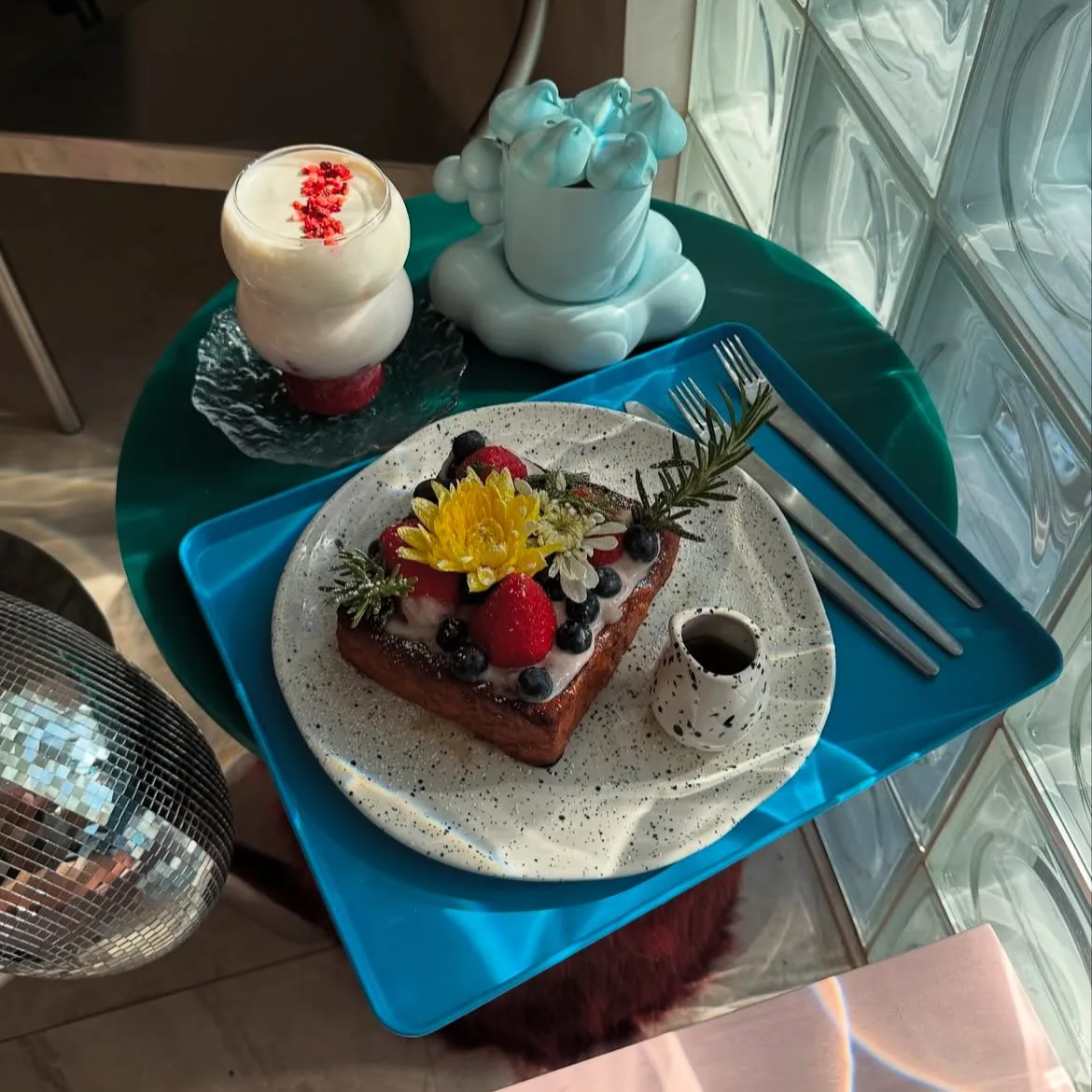 Dessert plate with berries and edible flowers beside a bear shaped drink