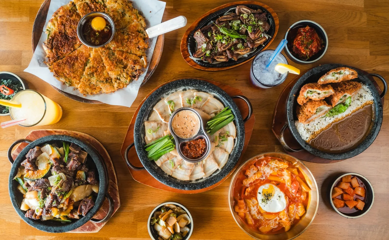Overhead spread of Korean stews, pancakes and small side dishes