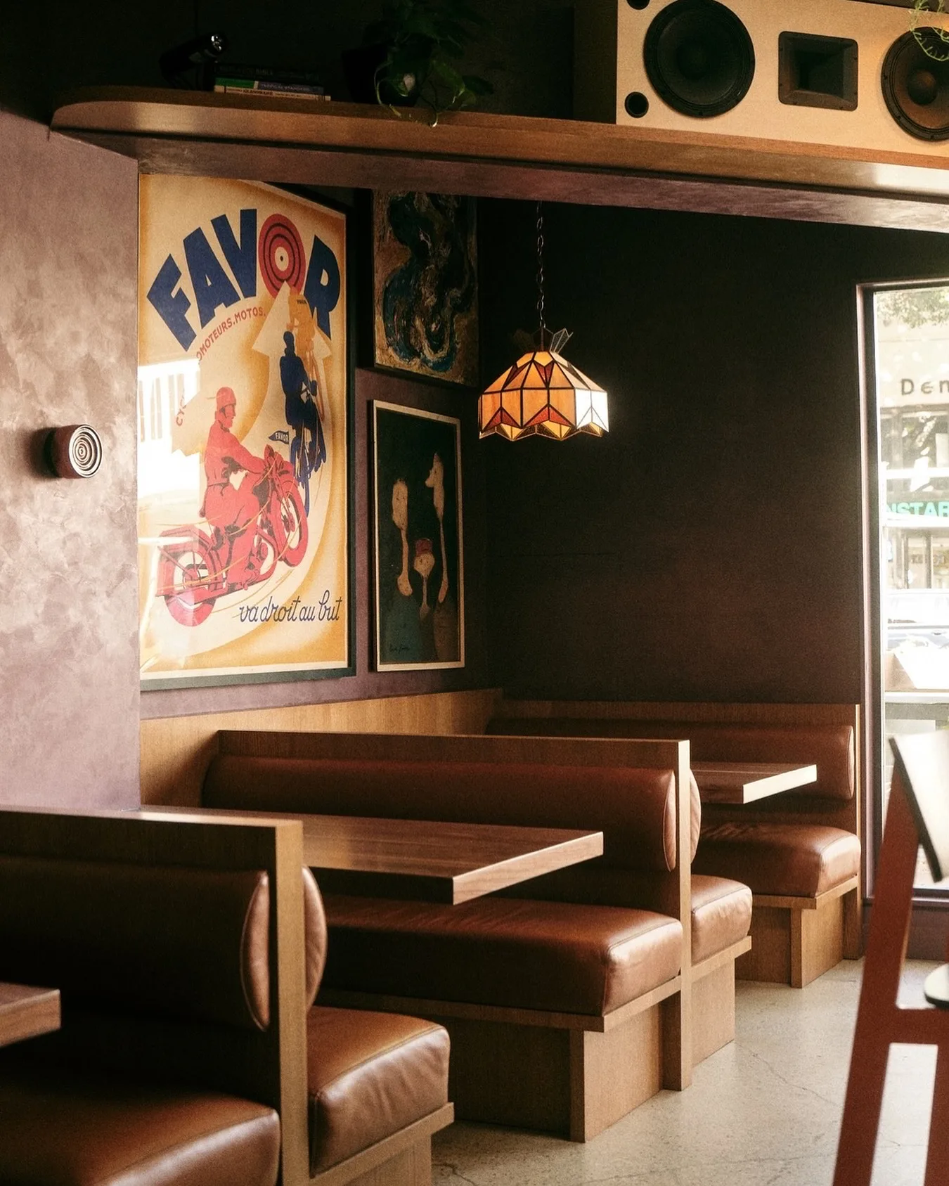 Casual bar with wooden booths, framed posters and a stained glass lamp