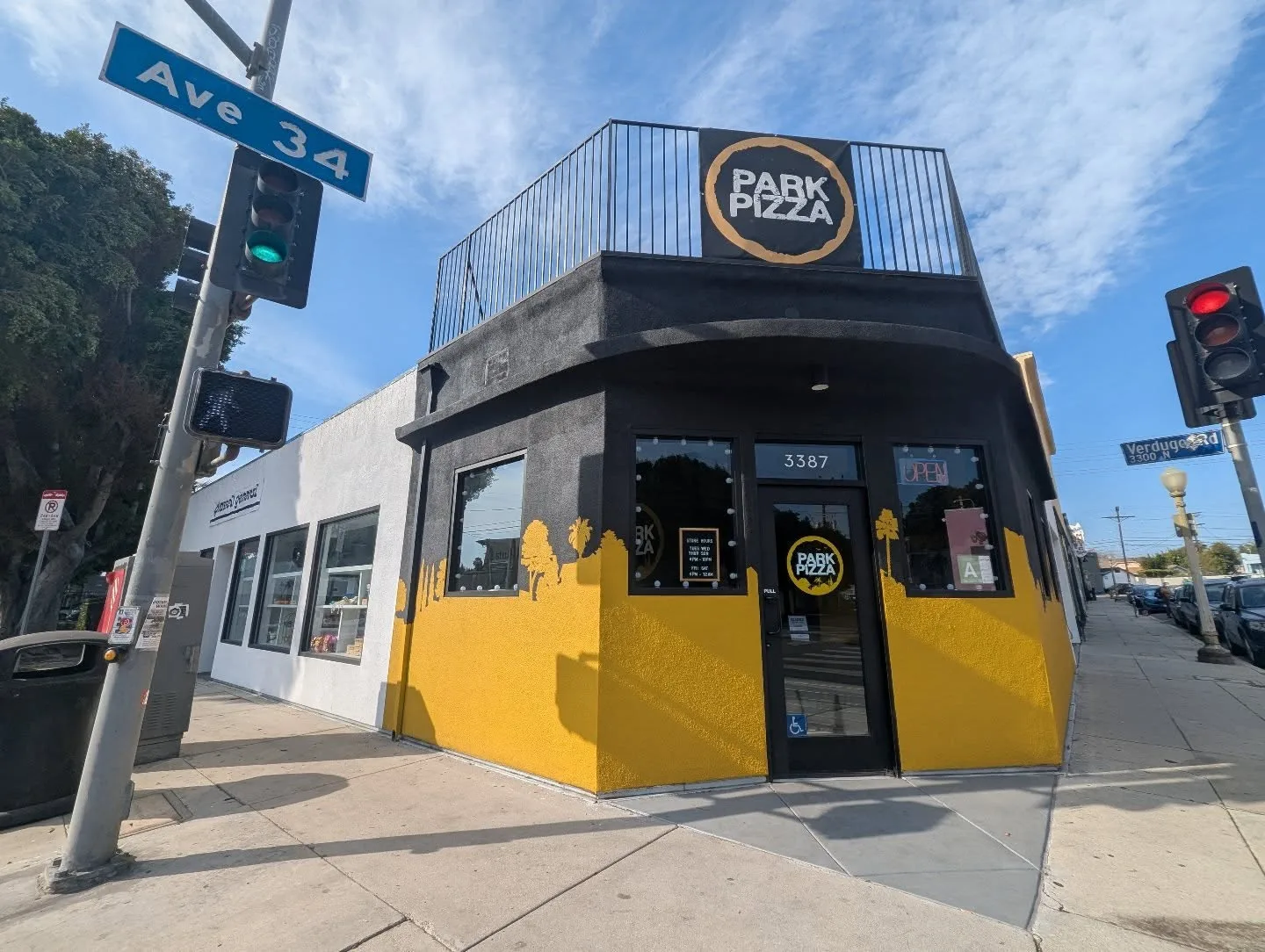 Yellow and black corner storefront beneath a street name sign