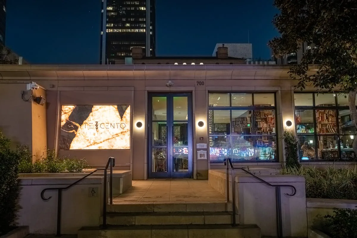 Lit restaurant entrance at dusk with glass doors and railings