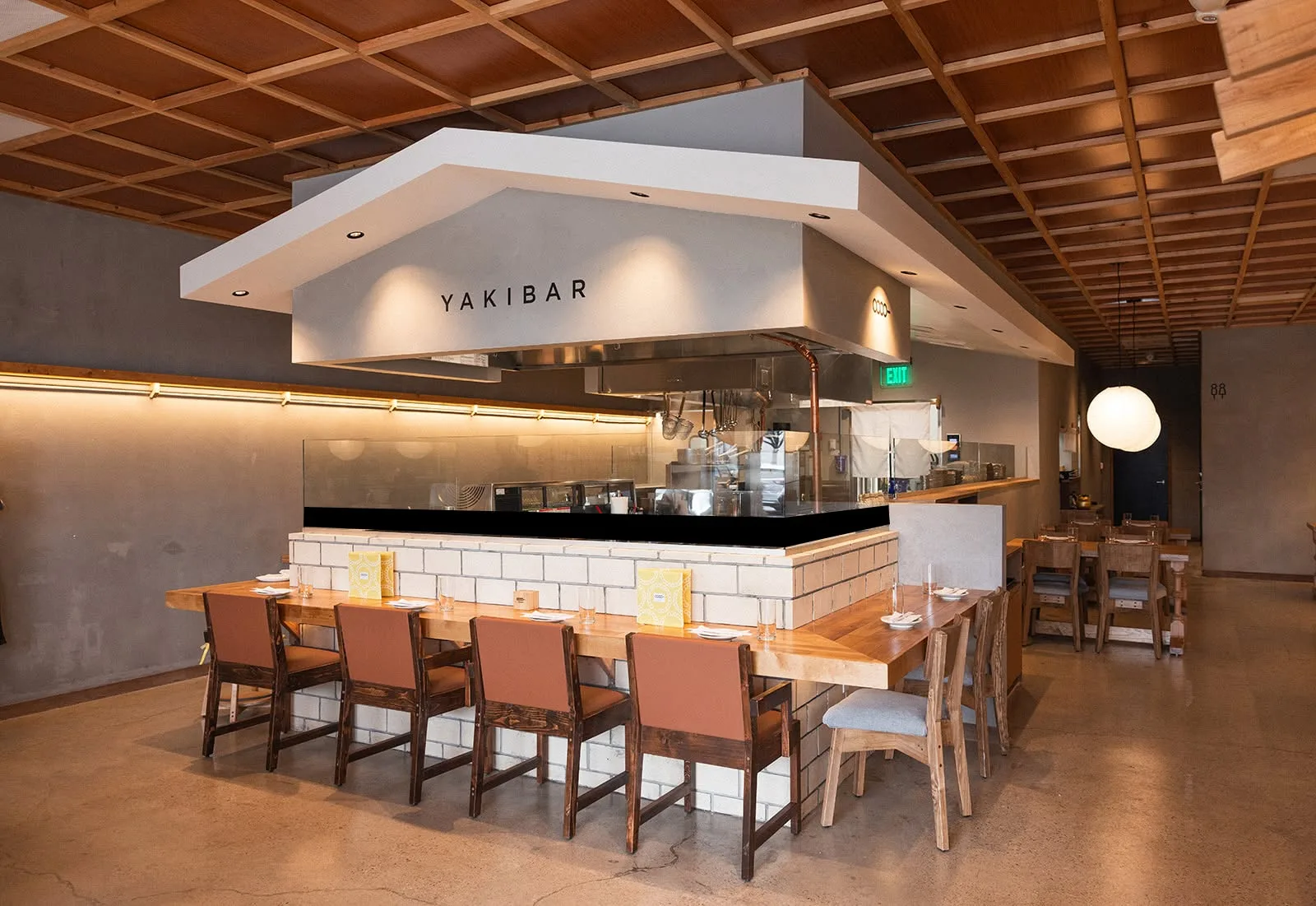 Counter seating with wooden stools beneath an open kitchen hood