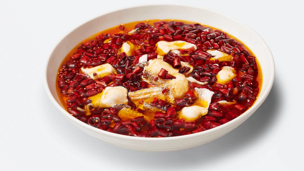 White bowl of fish fillets in a bright chilli broth