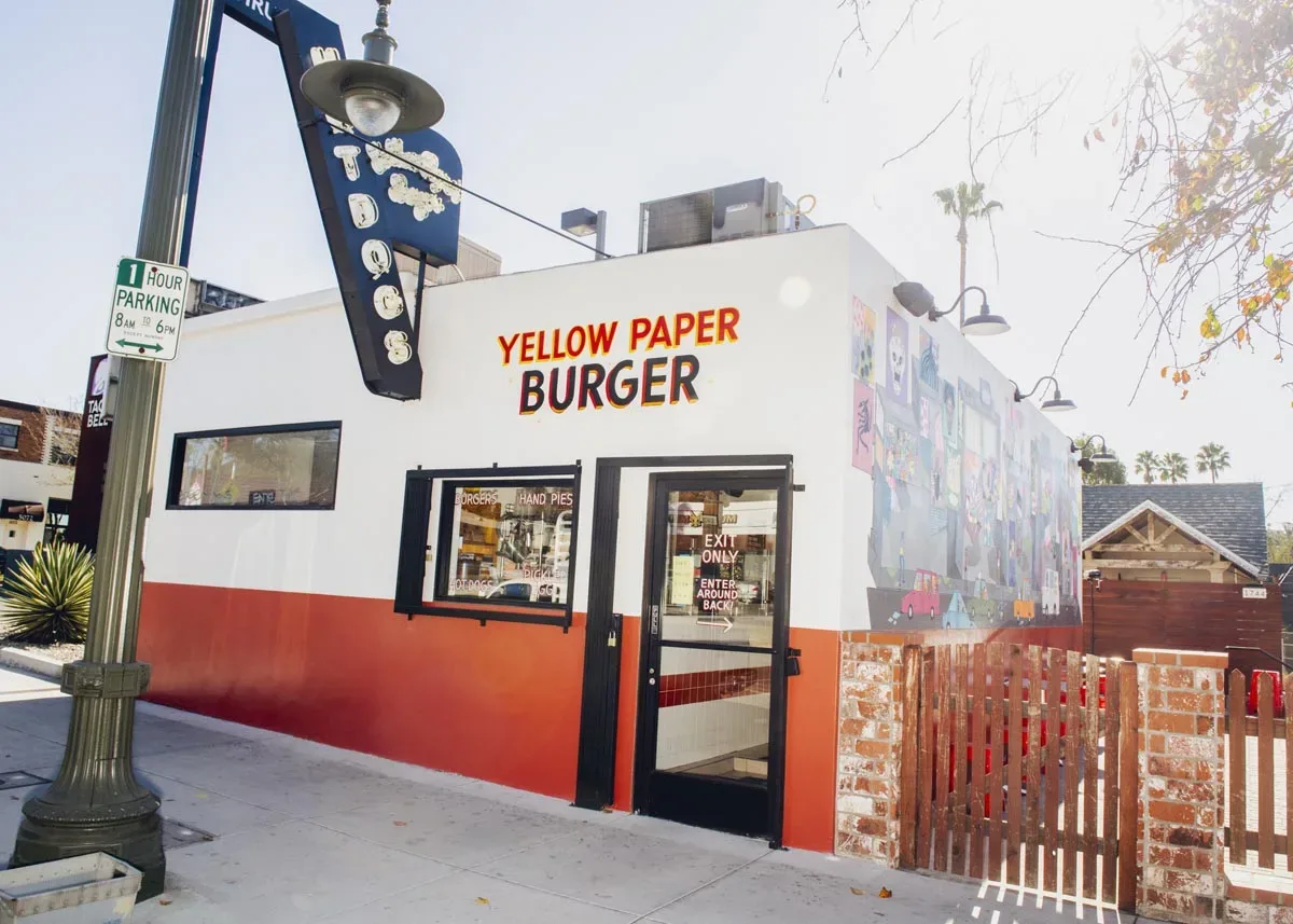 Small burger stand building with painted signage at a street corner