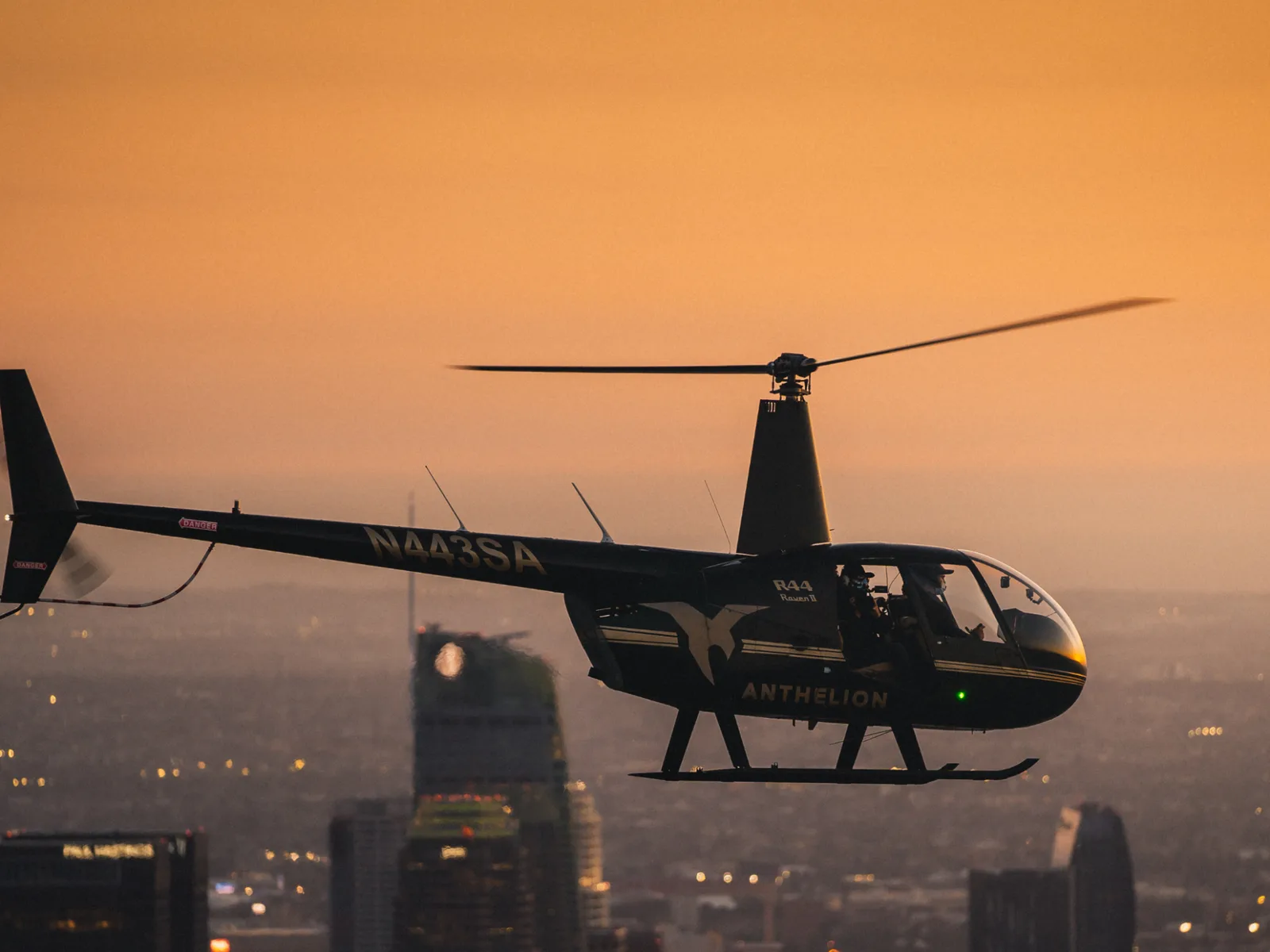 Small helicopter in flight above the city at sunset
