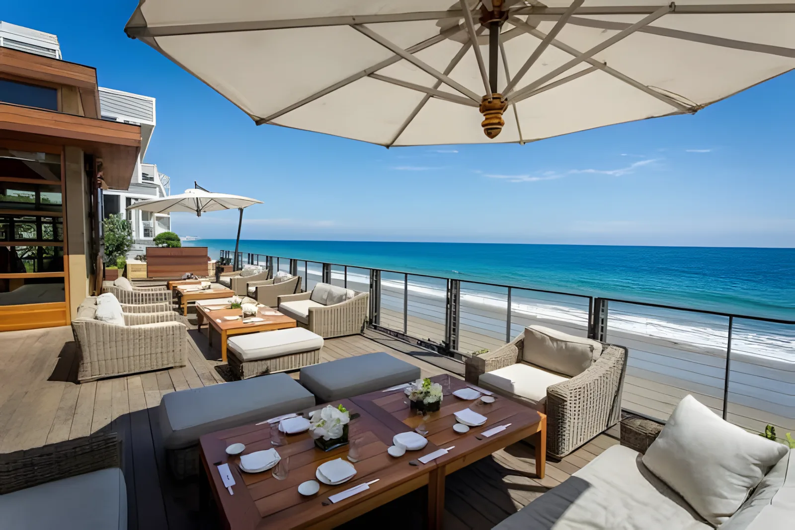 Patio table under an umbrella overlooking a beach and ocean