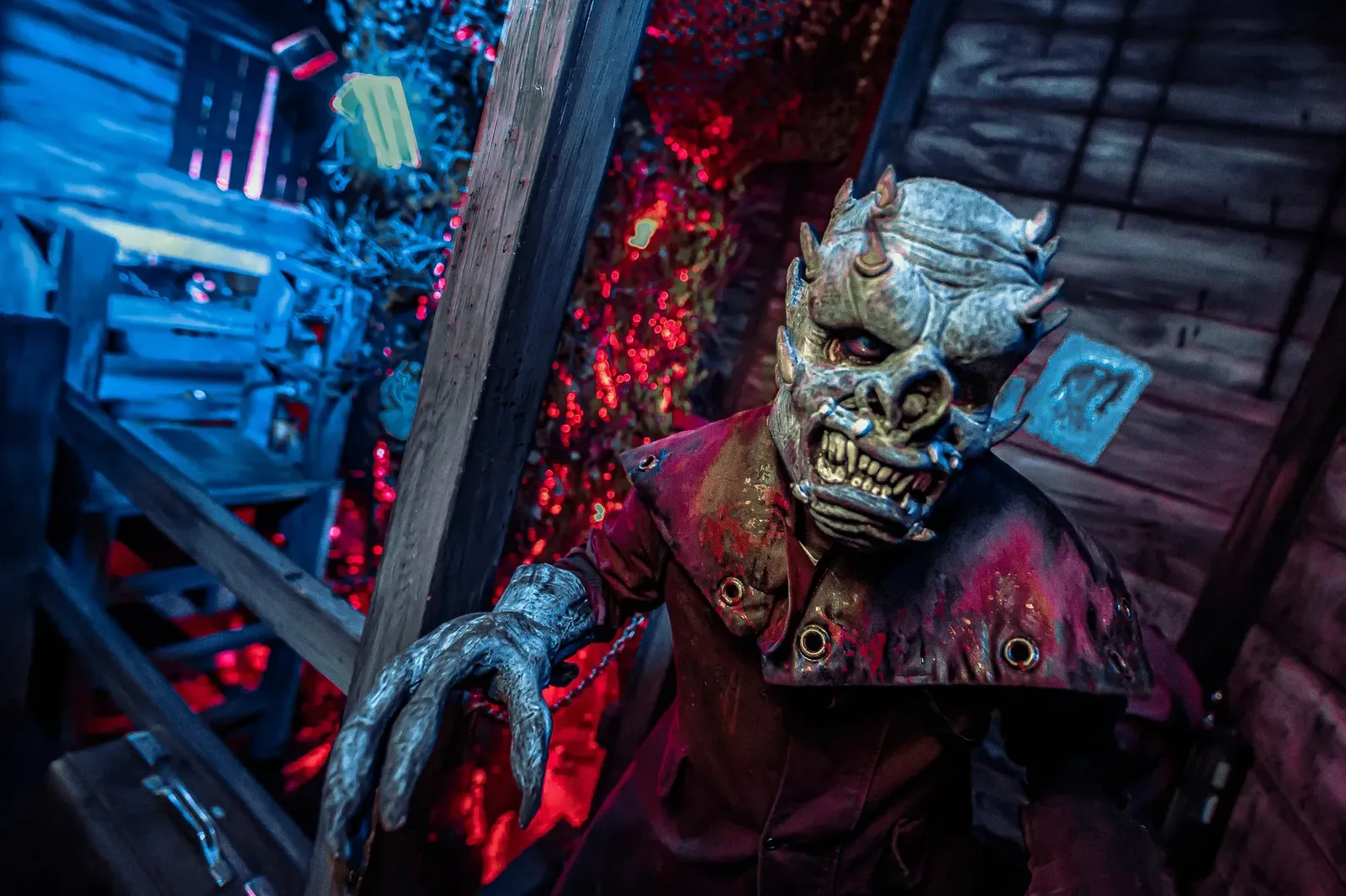 Costumed monster figure with clawed hand under red haunted lighting