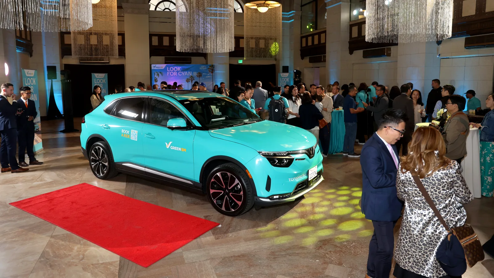 A cyan Green SM VinFast VF 8 on display beside a red carpet at the Los Angeles launch at The Majestic Downtown