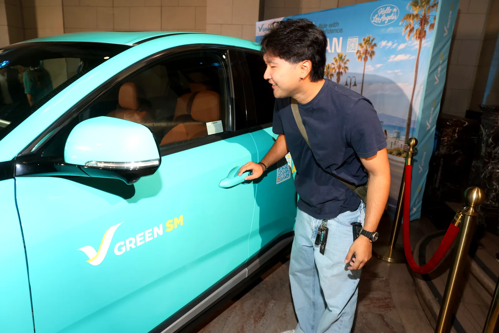 A guest opening the door of a cyan Green SM VinFast VF 8 at the launch event