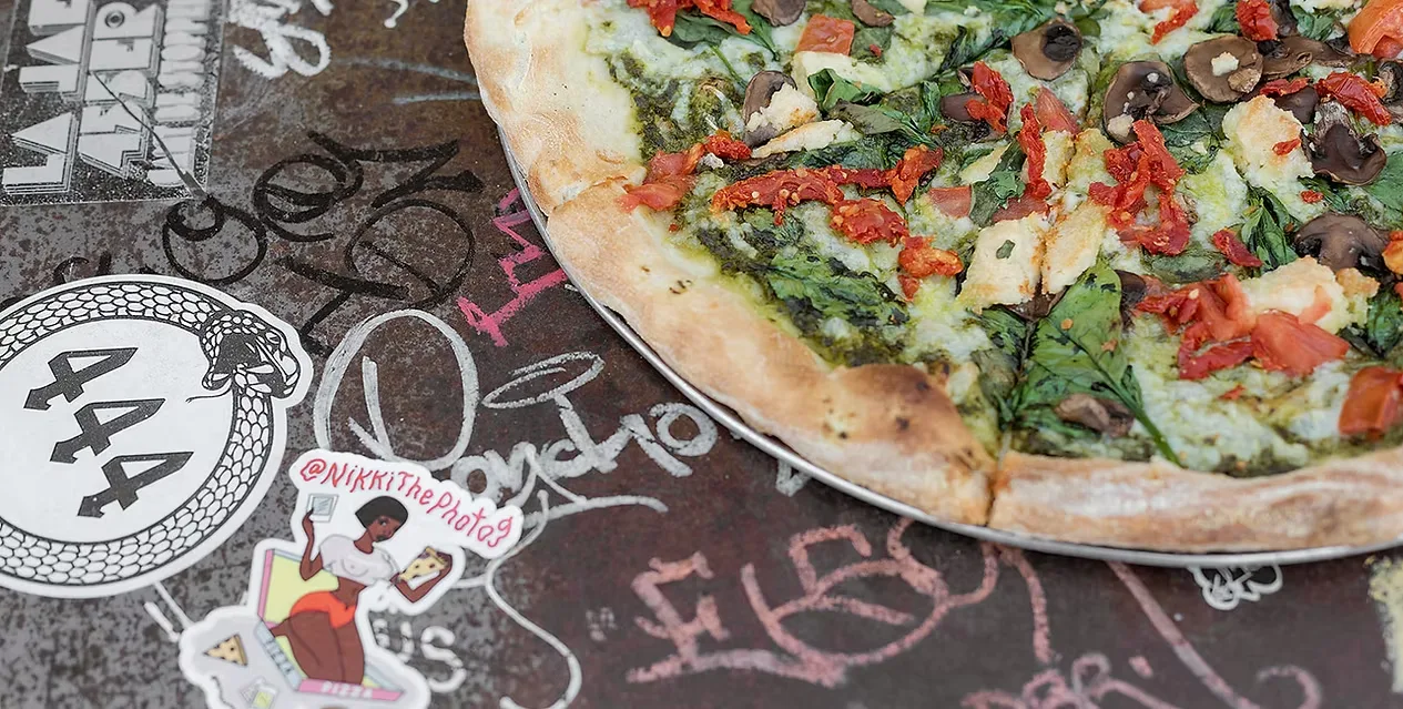 Close up of a whole pizza on a graffiti covered table