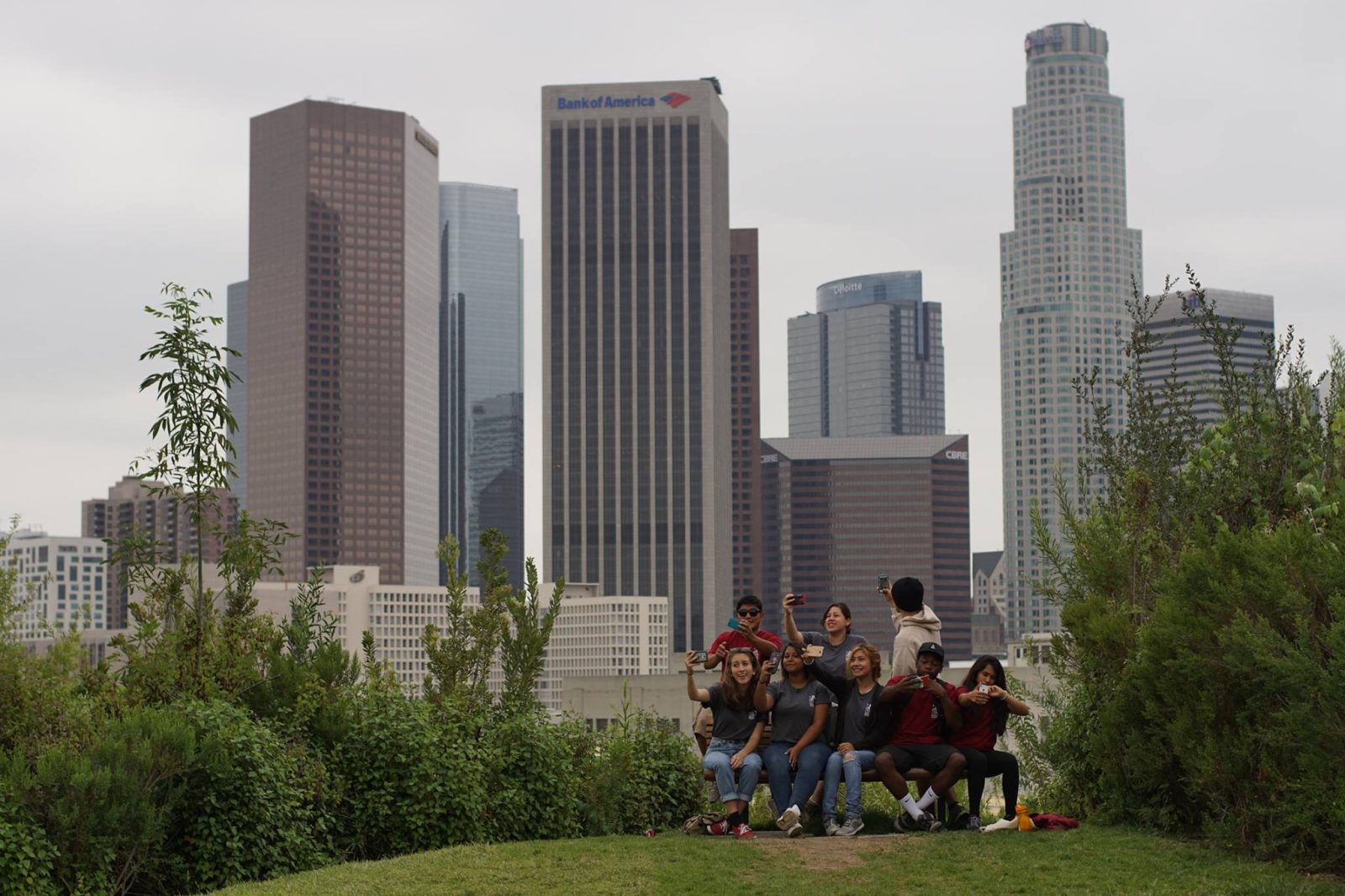 Visitors at an overlook bench on a natural trail at Vista Hermosa Natural Park, with downtown Los Angeles beyond.