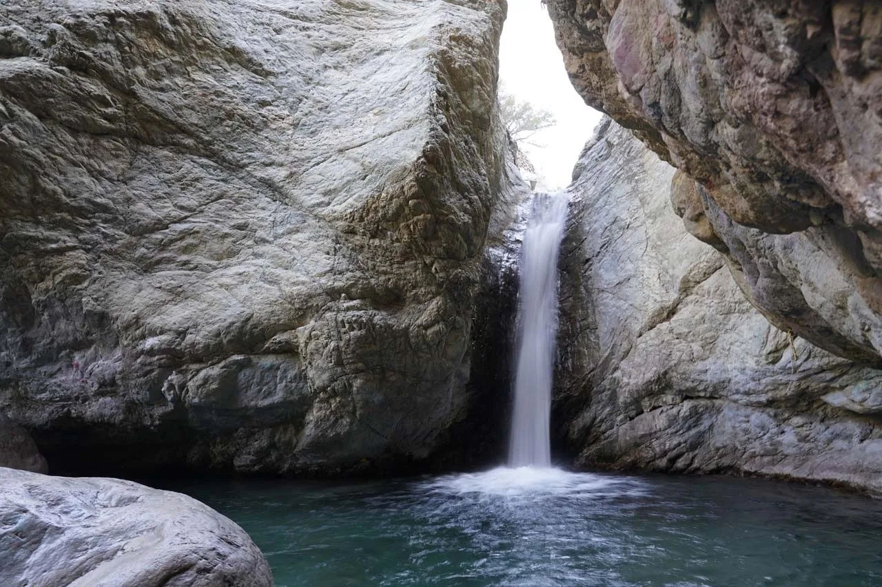 Waterfall dropping into a pool between smooth rock walls