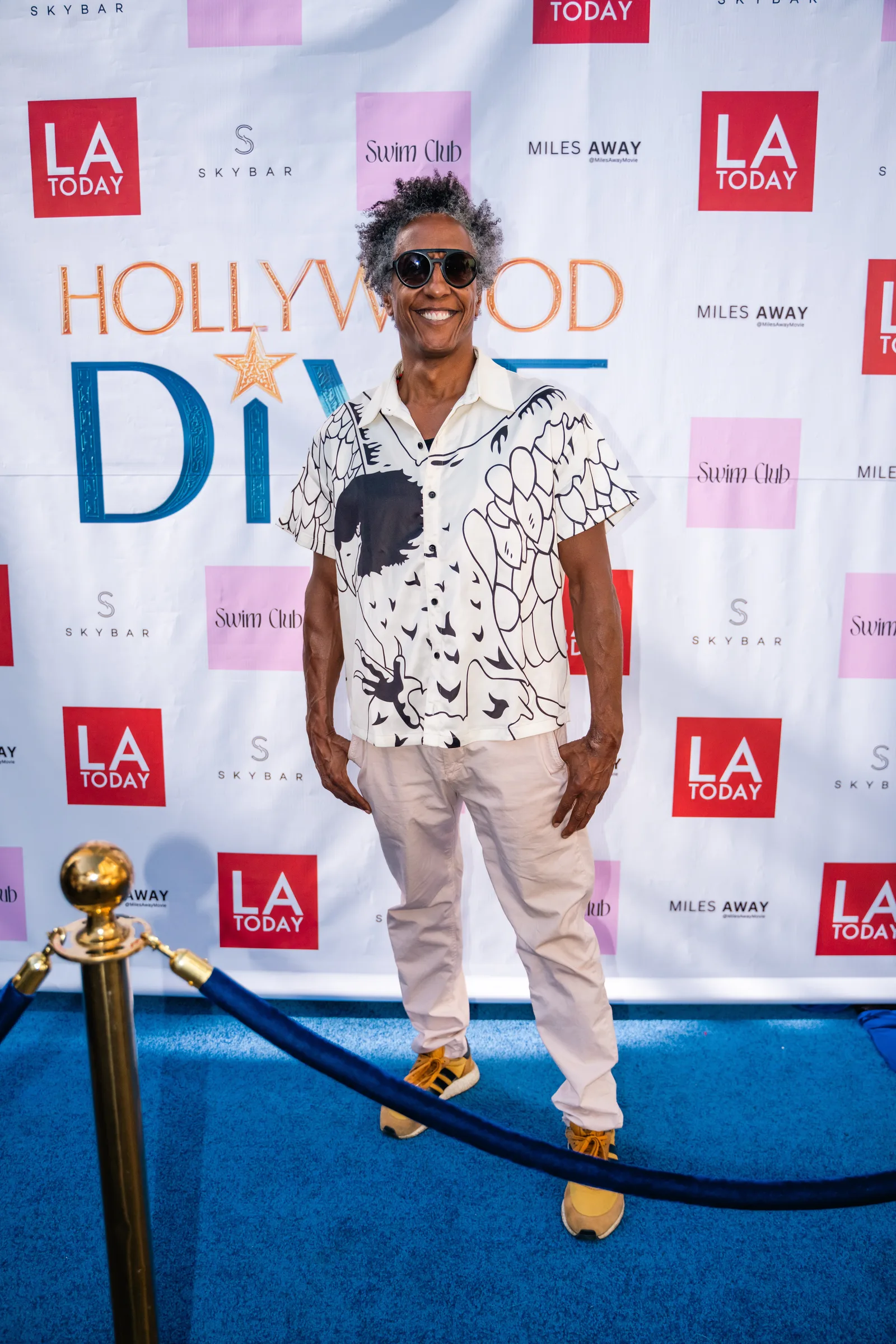 Guest in a printed short sleeve shirt poses at the Hollywood Dive backdrop