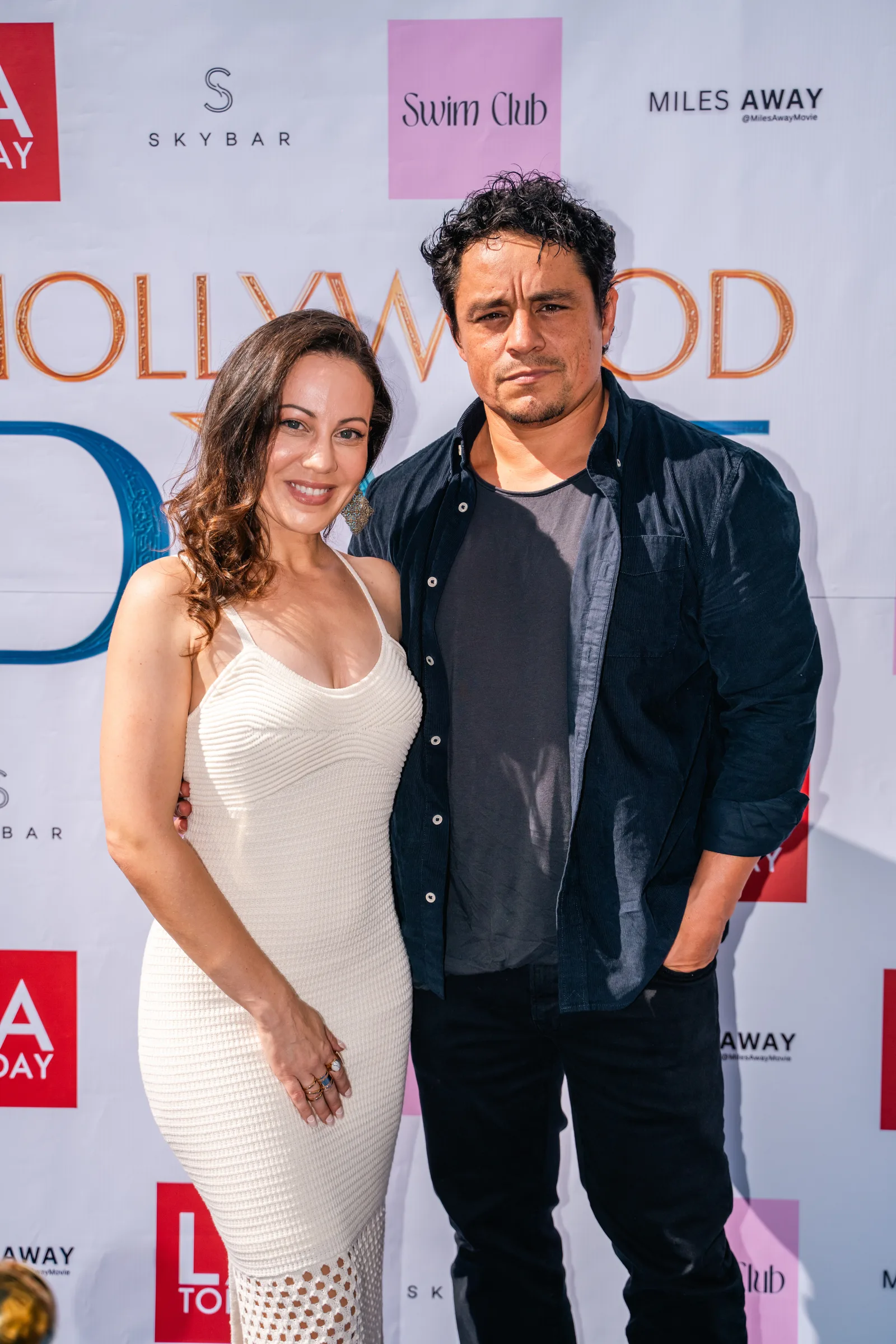 Two guests pose together in front of the Hollywood Dive sponsor wall