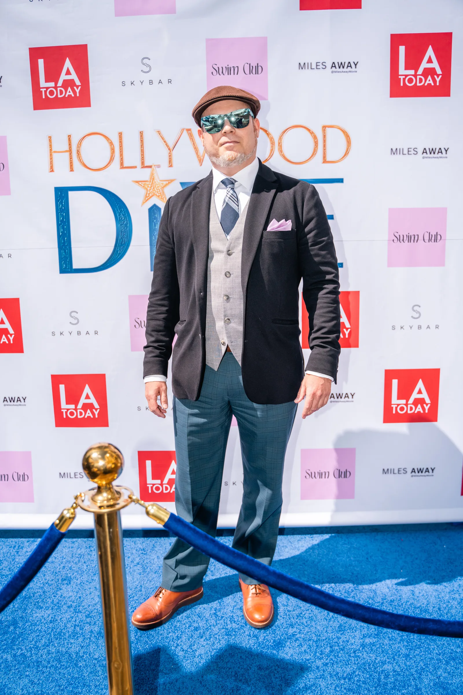 Guest in a three piece suit poses beside a gold globe stanchion