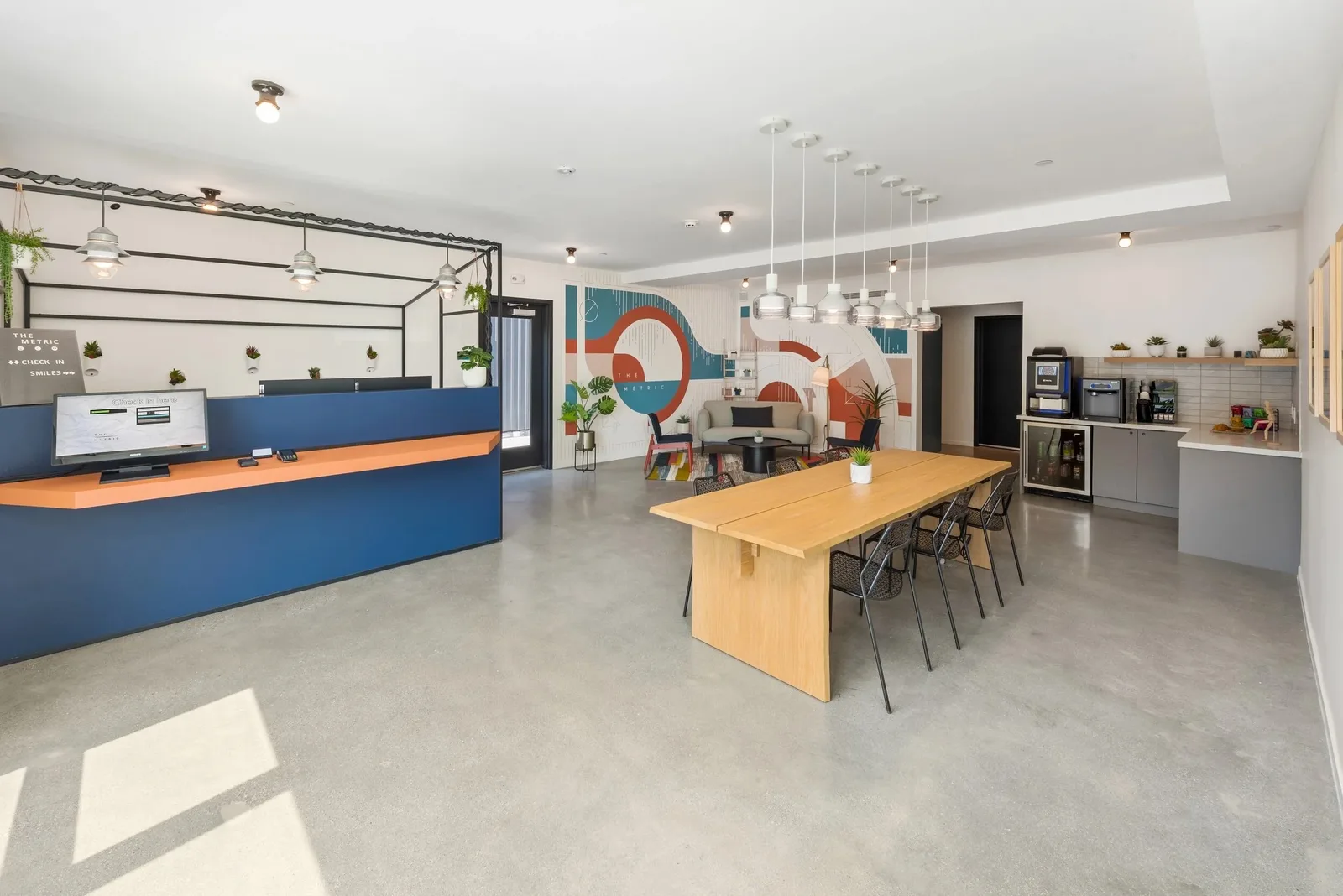Bright lobby with a reception desk, long table and kitchenette