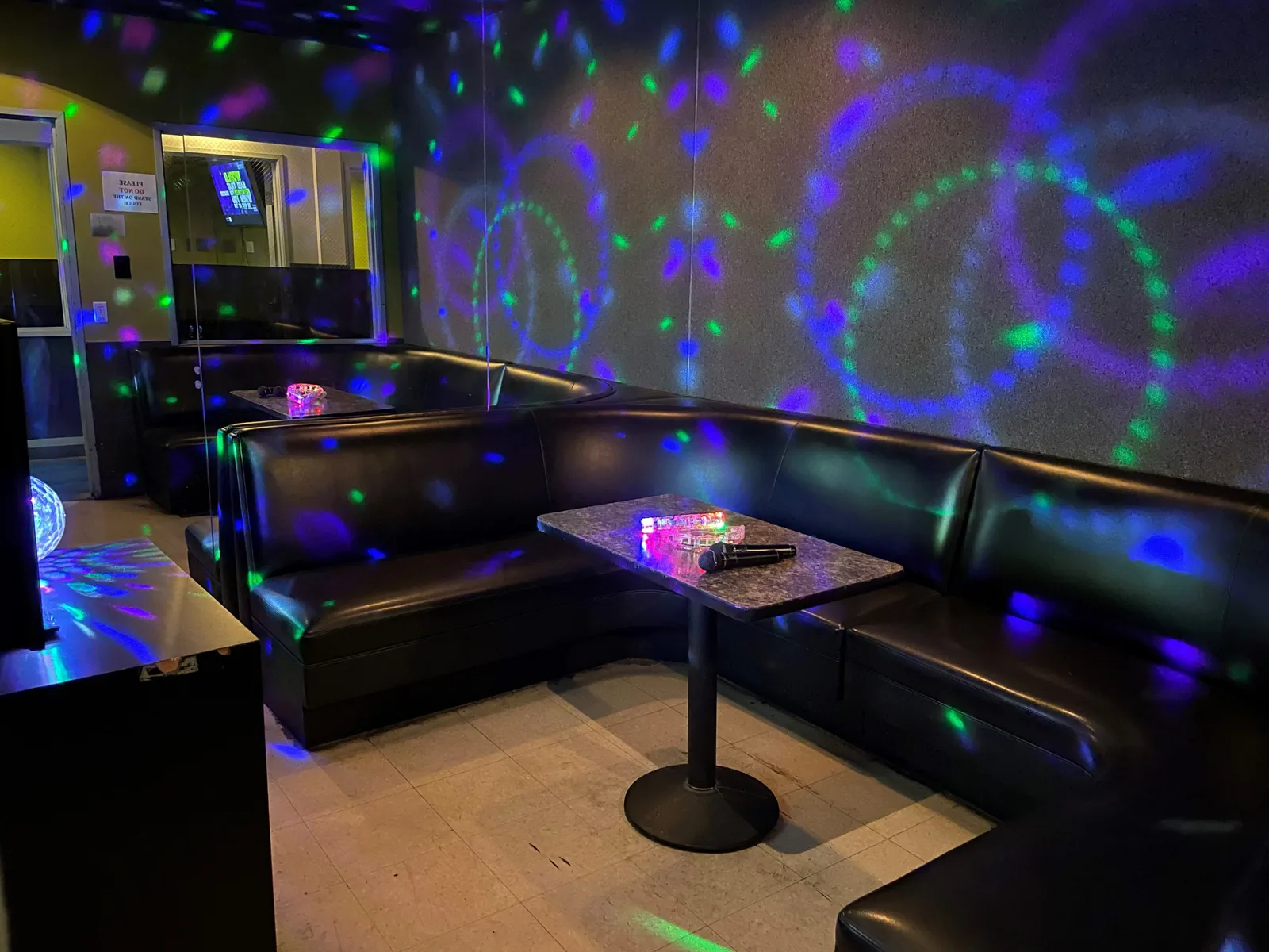 Dark karaoke room with booth seating and coloured ceiling light patterns