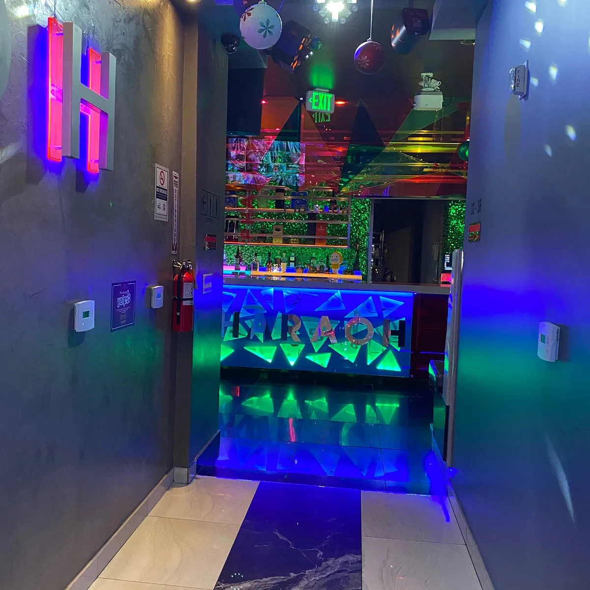 Dim corridor lit by blue and green neon with mirrored geometric panels