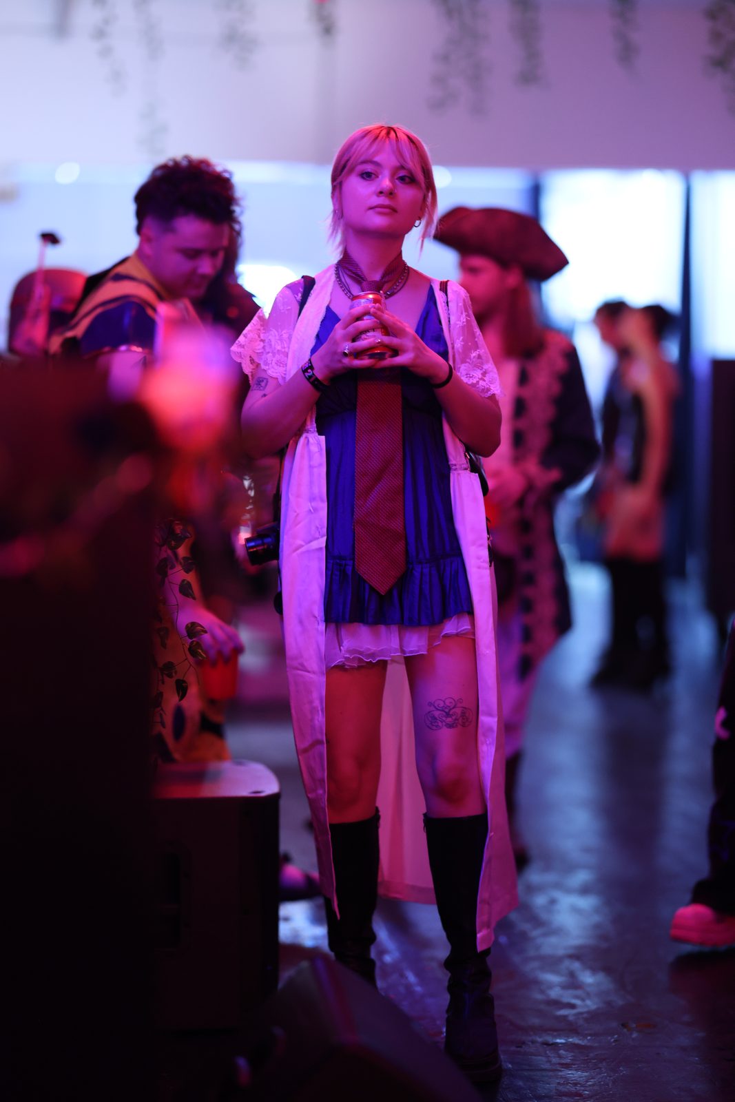A costumed guest stands in a corridor as others mingle behind