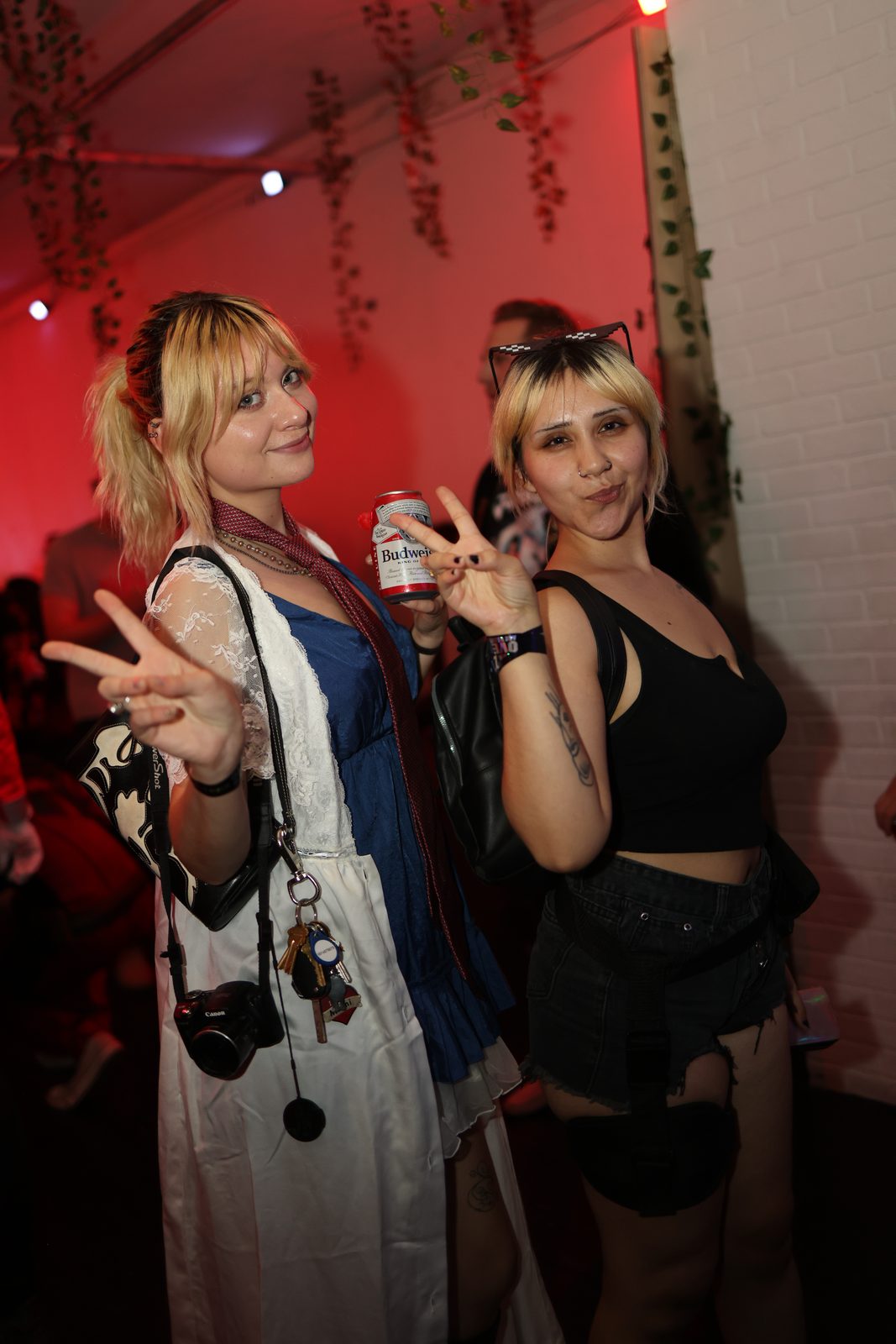 Two guests flash peace signs, one holding a canned drink