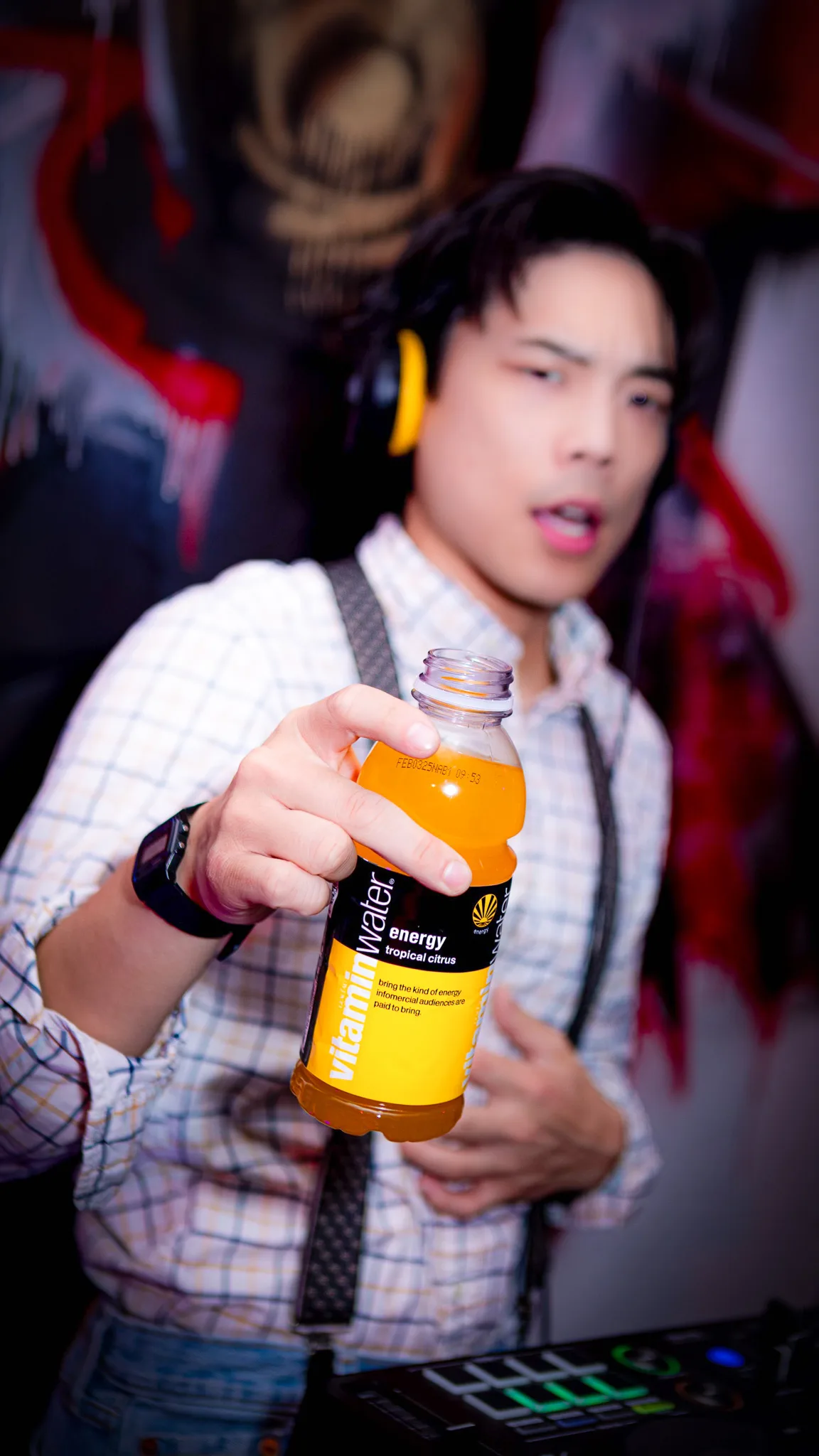 A guest holds an orange energy drink bottle toward the camera