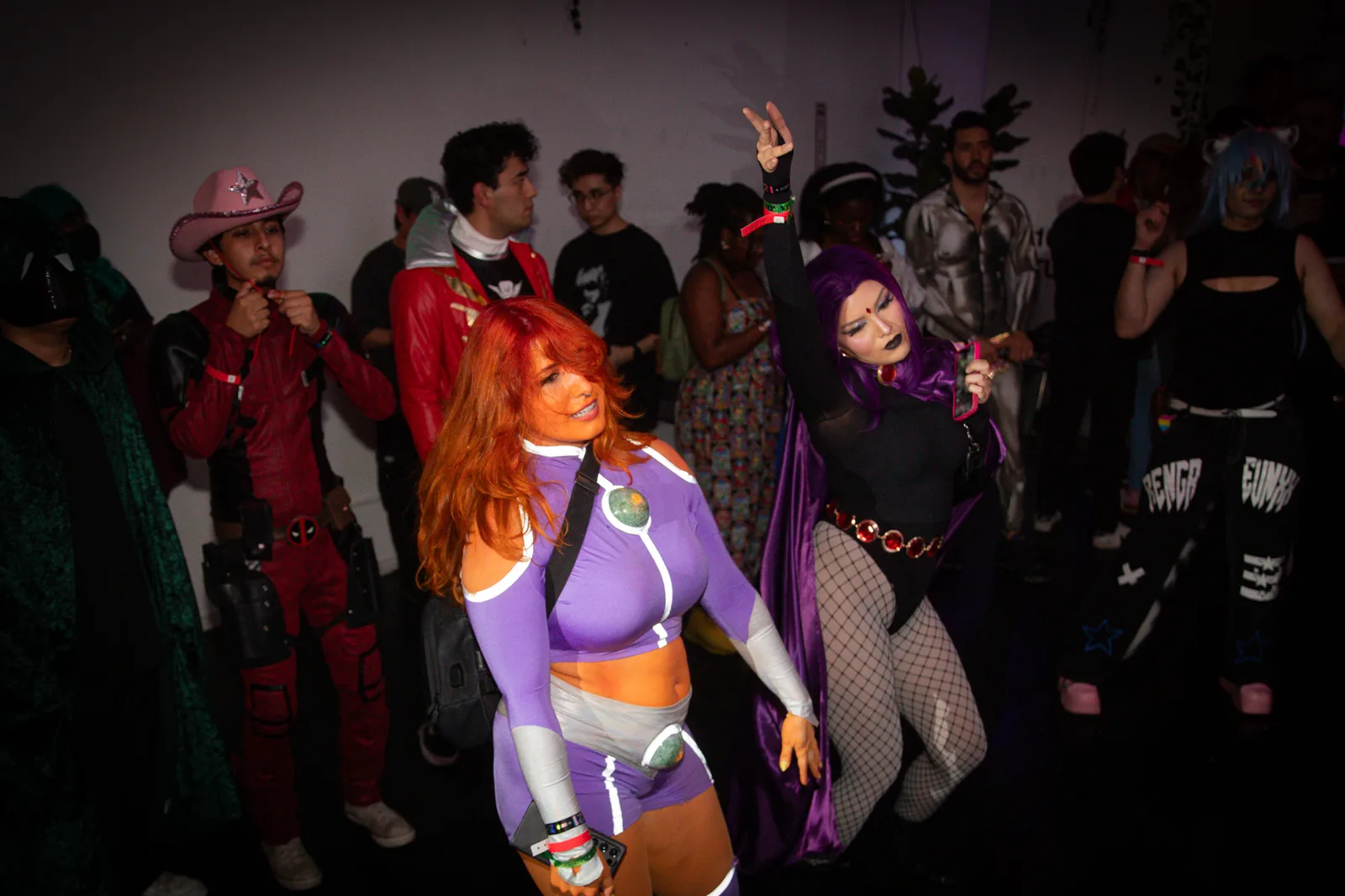 Guests in superhero and villain costumes dance in a dark room