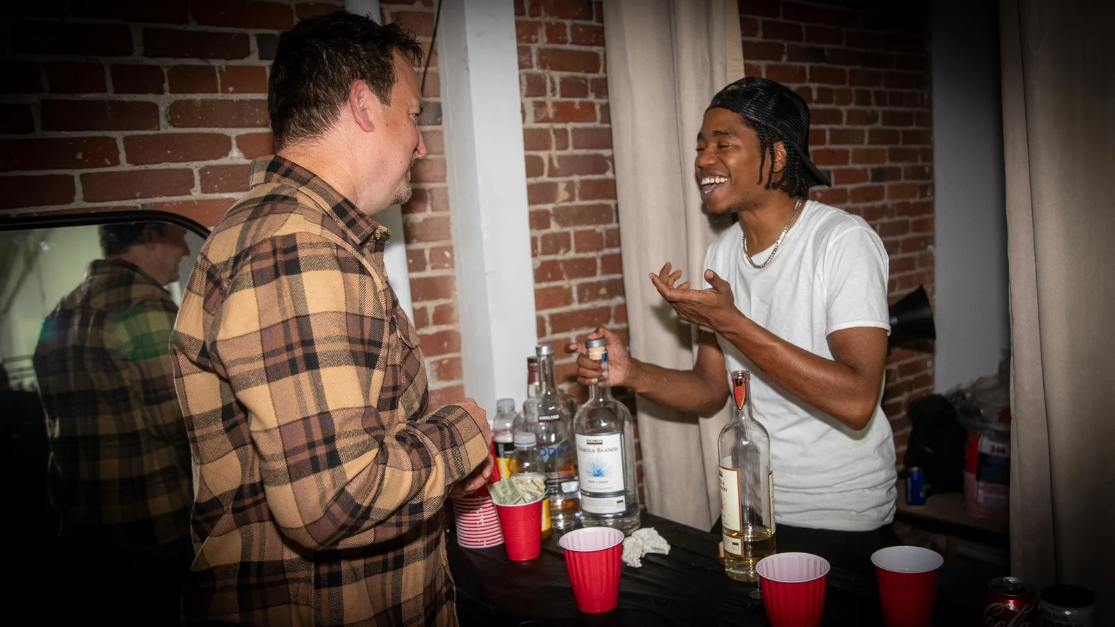 Two guests talk over a folding bar table stocked with bottles