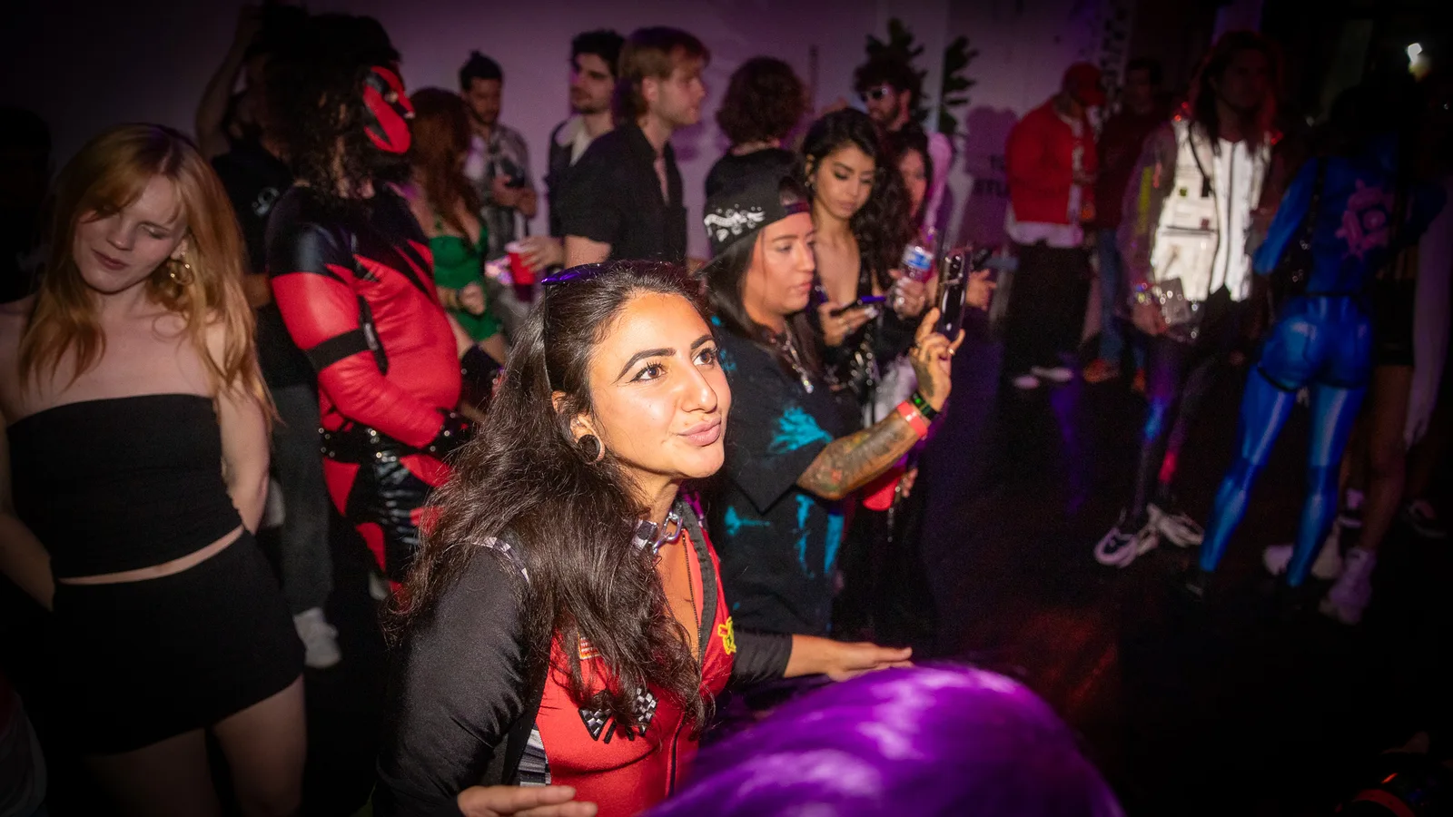 A guest leans toward the camera as costumed guests mingle behind