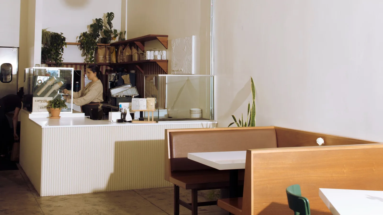 Amara Kitchen counter to order food with brown booth chairs and a white table, with very simple decoration